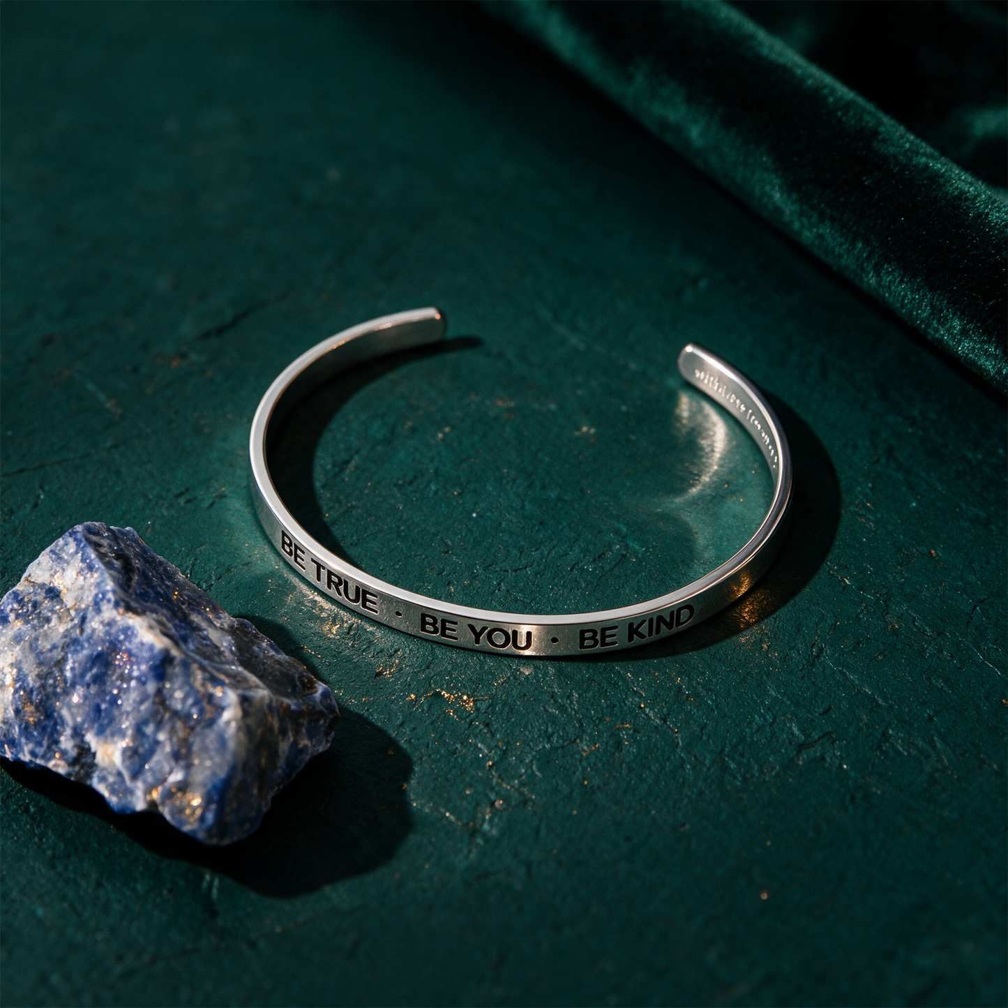 Armreif mit Gravur | Silber | "Be true - be you - be kind" – Produktansicht vor tiefem Smaragdgrün
