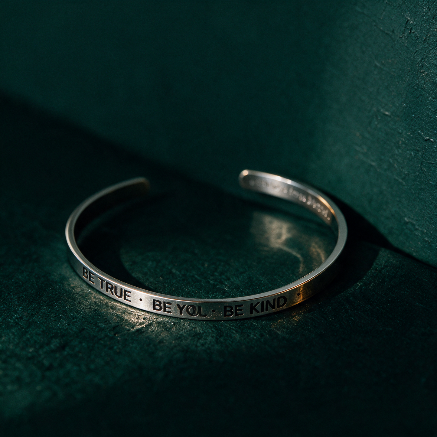 Armreif mit Gravur | Silber | "Be true - be you - be kind" – Material- und Setansicht vor tiefem Smaragdgrün
