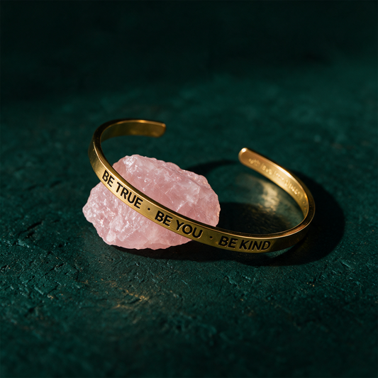 Armreif mit Gravur | vergoldet | "Be true - be you - be kind" – Produktansicht vor tiefem Smaragdgrün