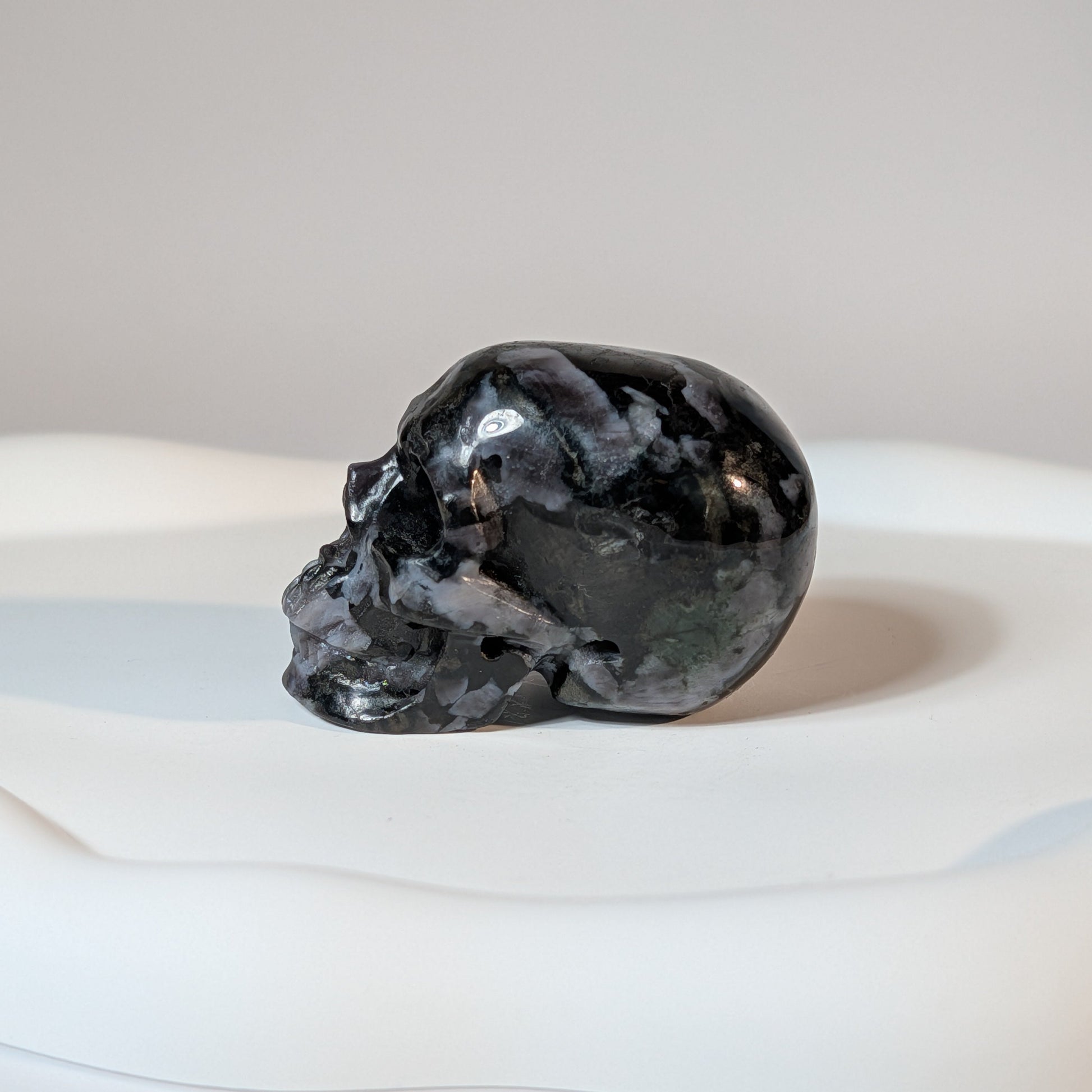 Kompakter Kristallschädel Fayt aus Nephelin, mit einer hellen, von dunklen Mineralien gesprenkelten Gesteinsmatrix.
