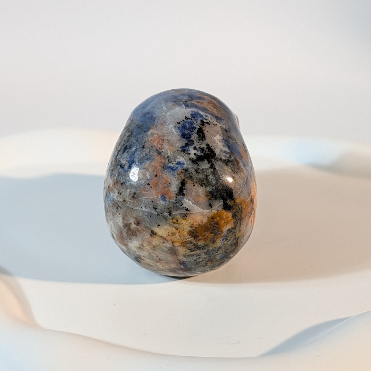 Massiver Kristallschädel Brok aus Sodalith mit zerrissener, tiefblauer, aschgrauer und rostig oranger Gesteinsmatrix.