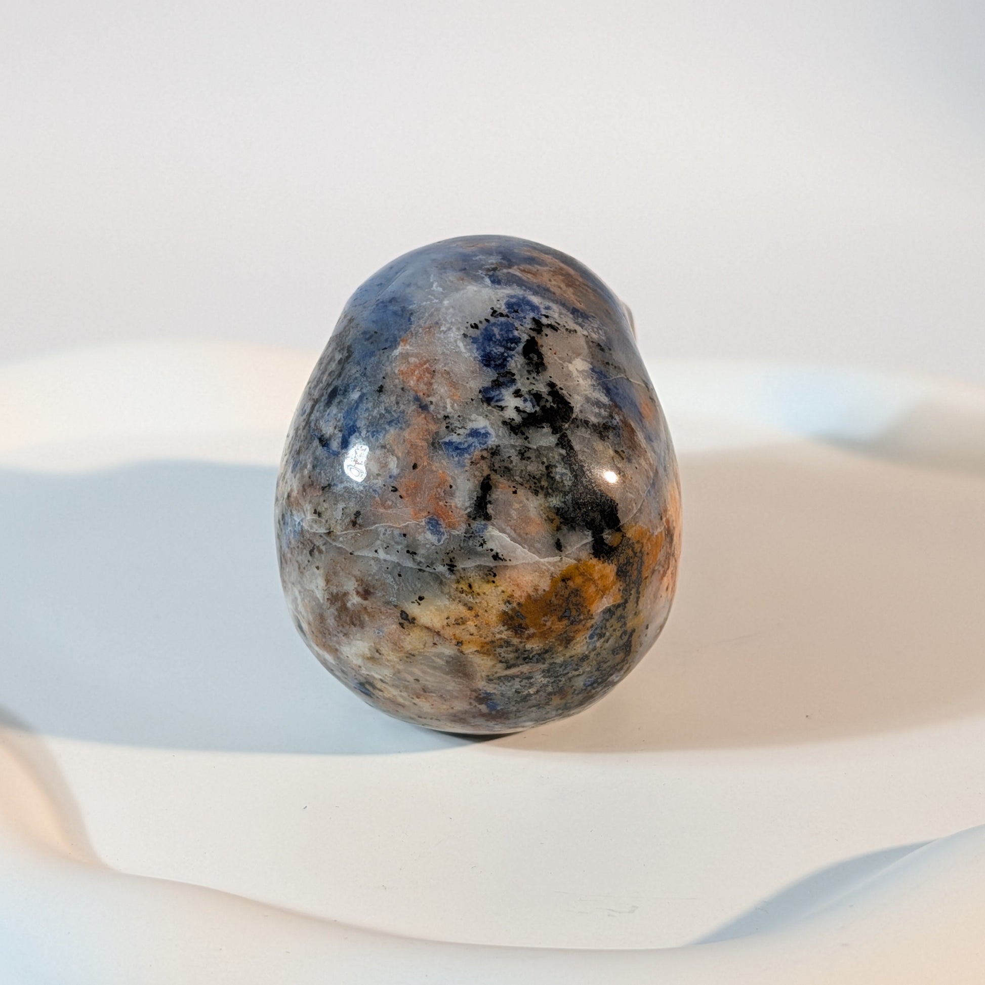 Massiver Kristallschädel Brok aus Sodalith mit zerrissener, tiefblauer, aschgrauer und rostig oranger Gesteinsmatrix.