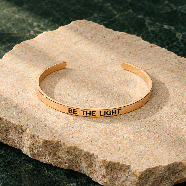 Rosévergoldeter Armreif mit Gravur „Be the light“ vor hellem Hintergrund