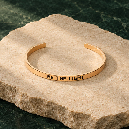 Rosévergoldeter Armreif mit Gravur „Be the light“ vor hellem Hintergrund