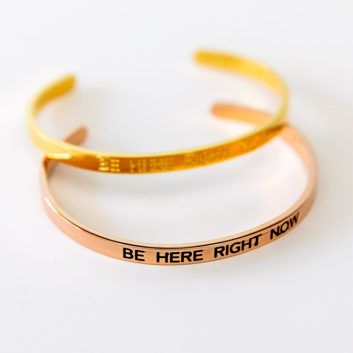 Rosévergoldeter Armreif mit Gravur „Be here right now“ vor hellem Hintergrund