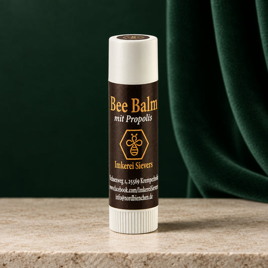 Bee Balm mit Propolis der Imkerei Sievers, dunkelbrauner Lippenpflegestift mit weißer Kappe vor orangem Hintergrund