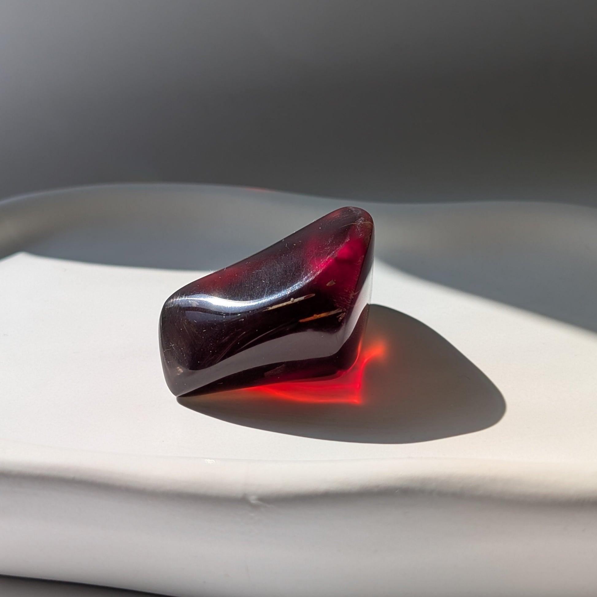 Bernstein Talisman "Rubin der Vorzeit" in dunkler, tropfenartiger Form mit rotem Kern.