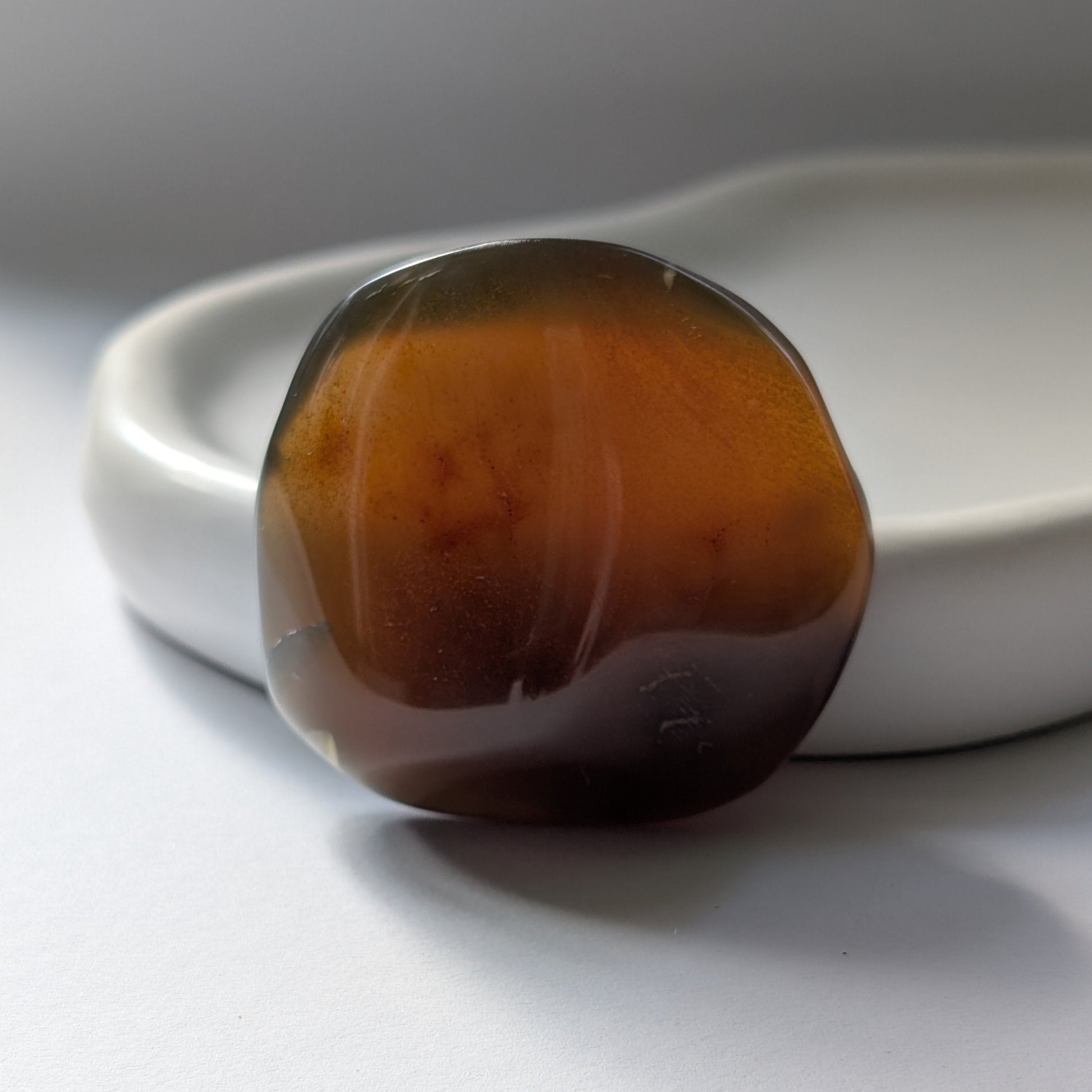 Bernstein Talisman "Tropfen der Vorzeit" in dunkler, tropfenartiger Form mit rotem Kern.