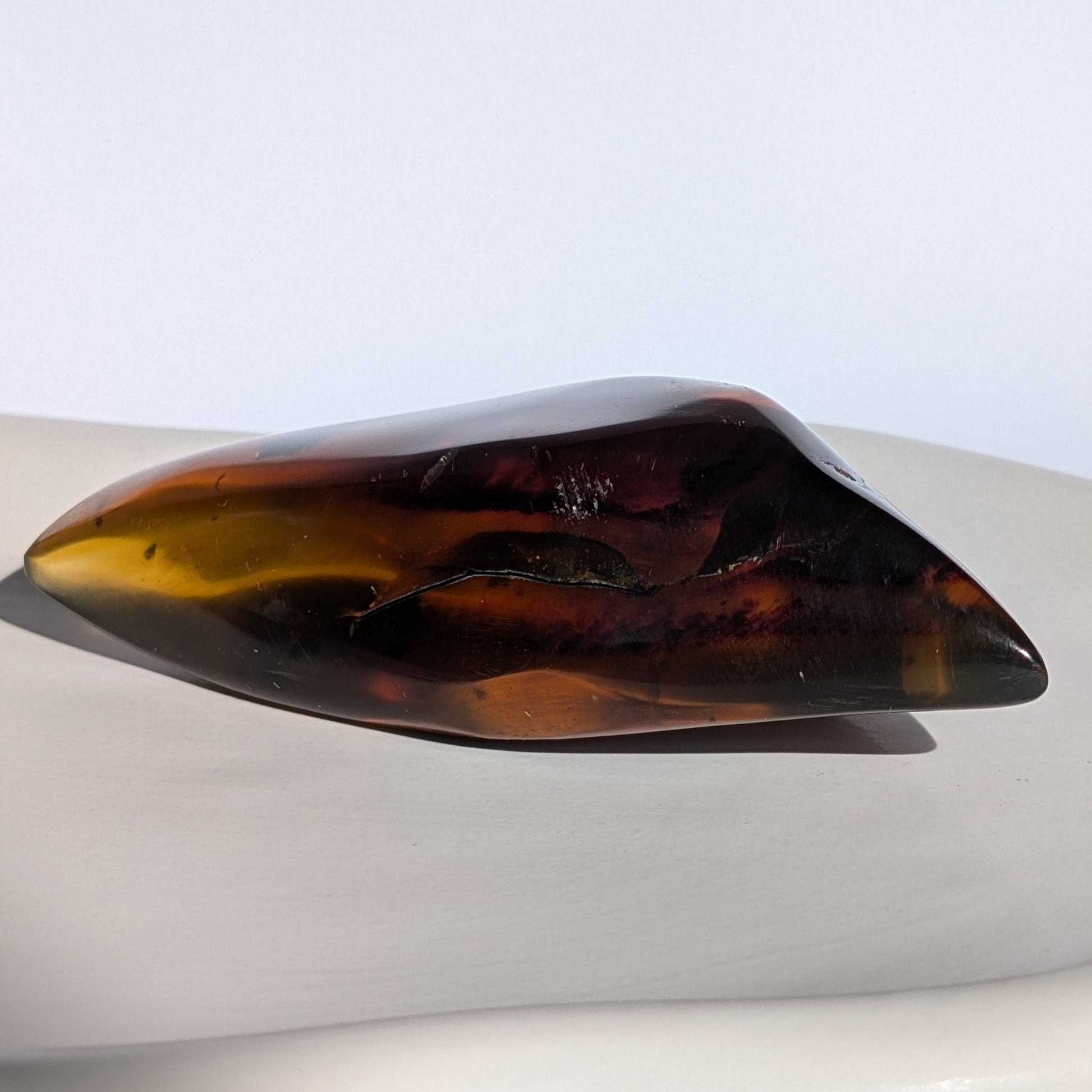 Bernstein Unikat "Das Blatt der Vorzeit" in dunkler, flammenartiger Form mit rotem Kern.
