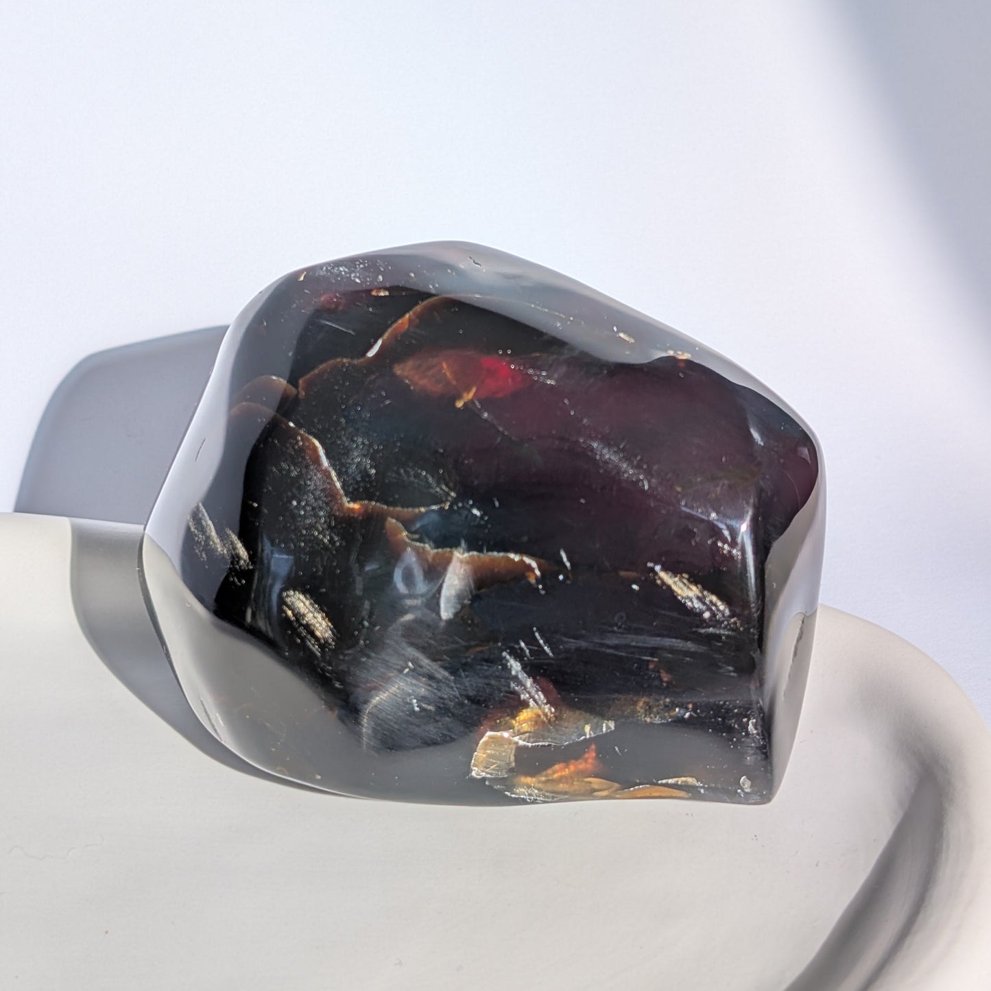 Bernstein Unikat "Der Monolith der Vorzeit" in dunkler, unregelmäßiger Form mit rotem Kern.