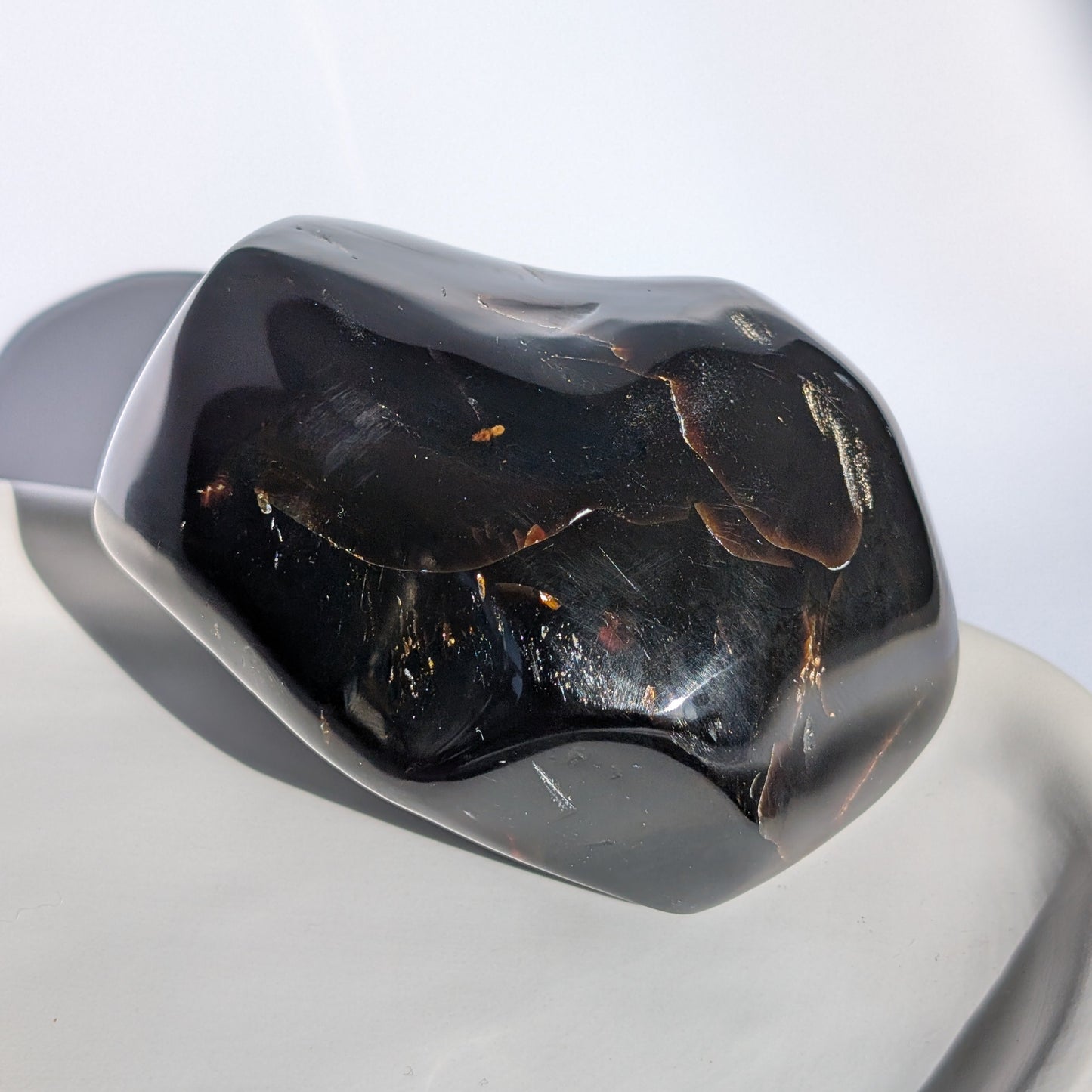 Bernstein Unikat "Der Monolith der Vorzeit" in dunkler, unregelmäßiger Form mit rotem Kern.