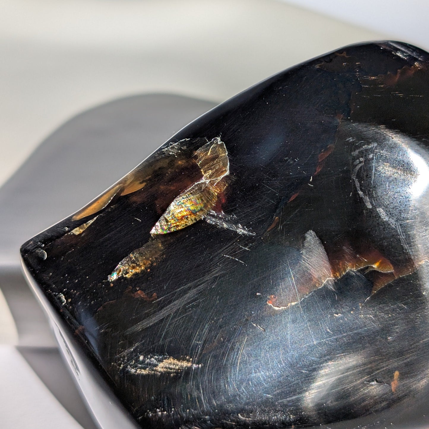 Bernstein Unikat "Der Monolith der Vorzeit" in dunkler, unregelmäßiger Form mit rotem Kern.