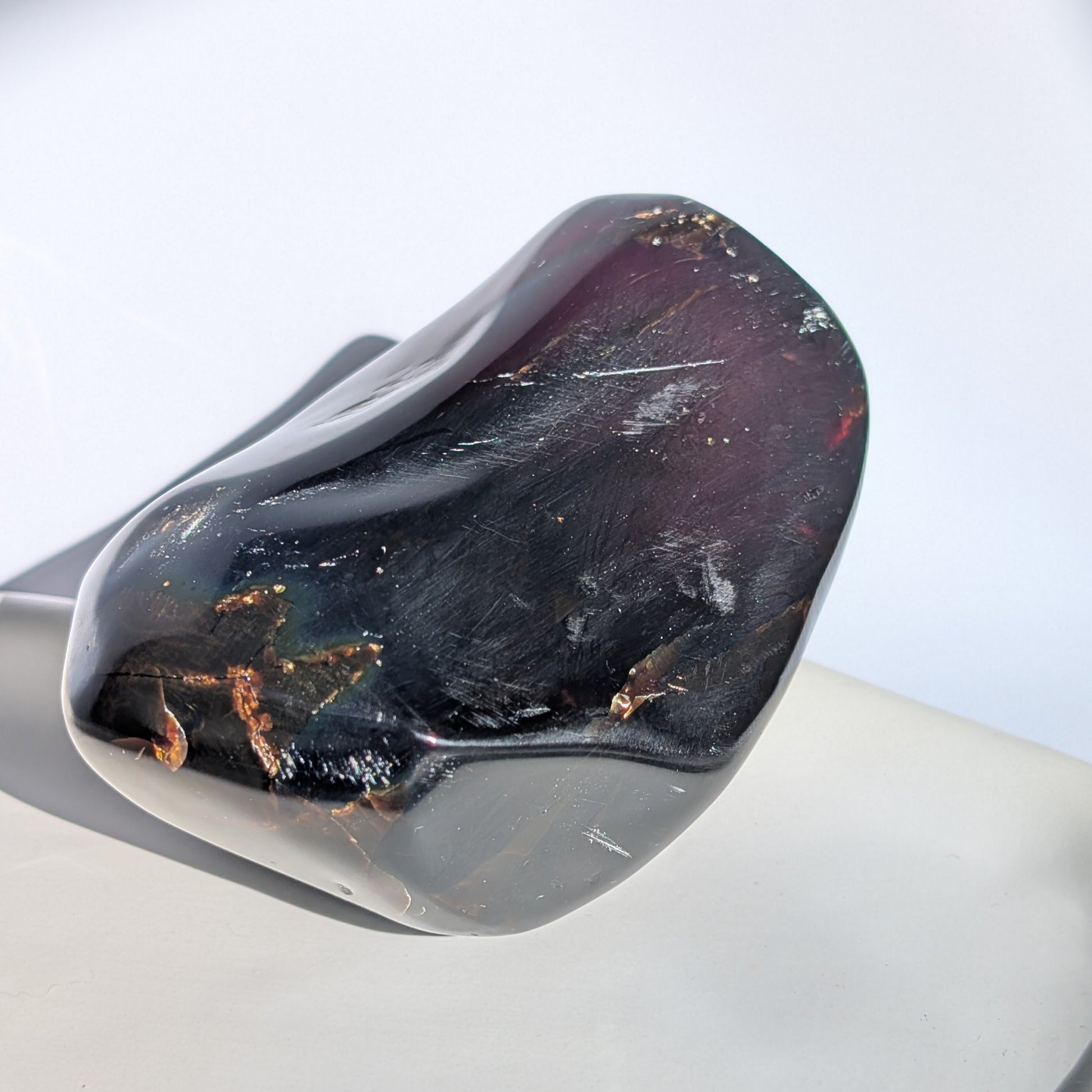 Bernstein Unikat "Der Monolith der Vorzeit" in dunkler, unregelmäßiger Form mit rotem Kern.