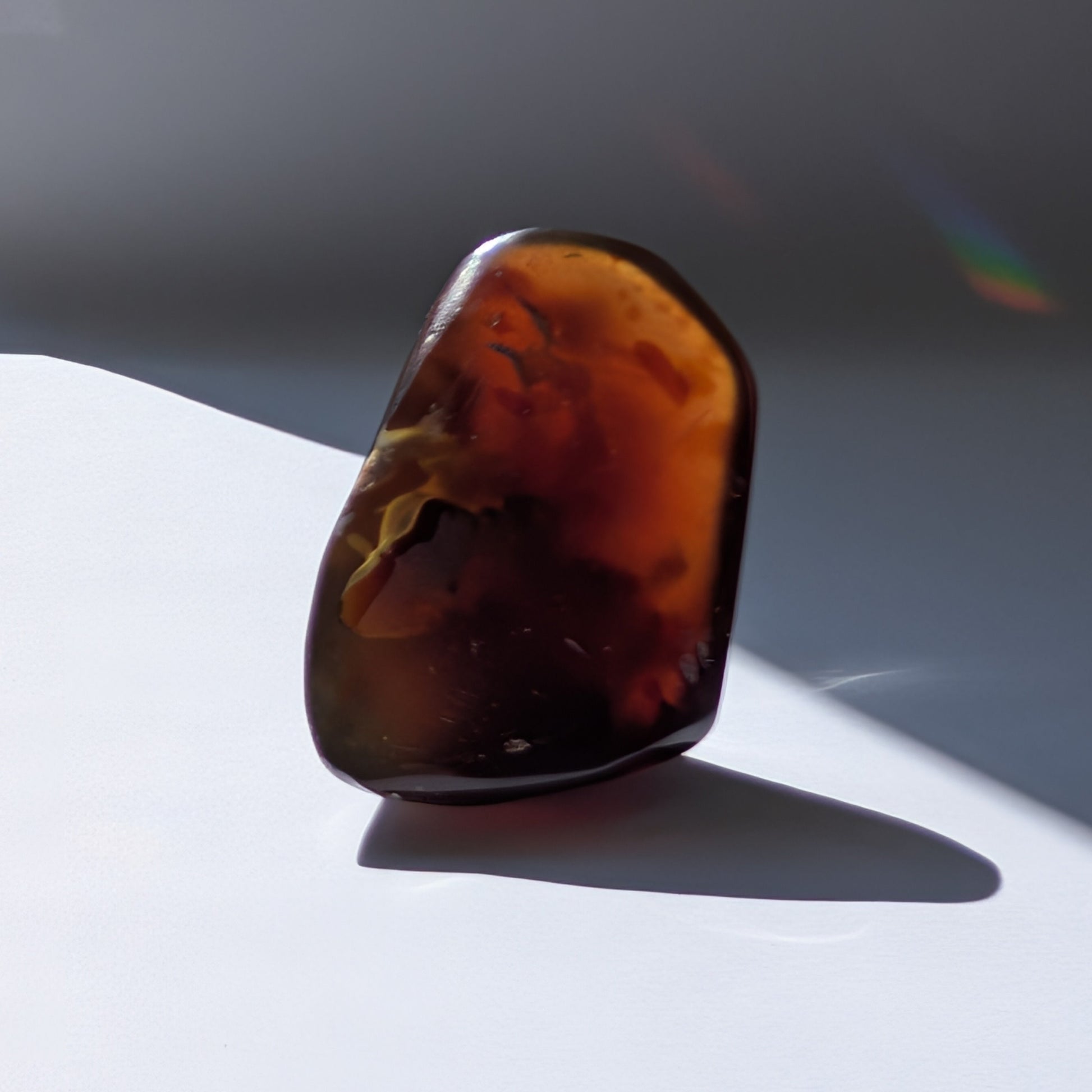 Bernstein Unikat "Die Träne der Sonne" in dunkler, tropfenartiger Form mit rotem Kern.