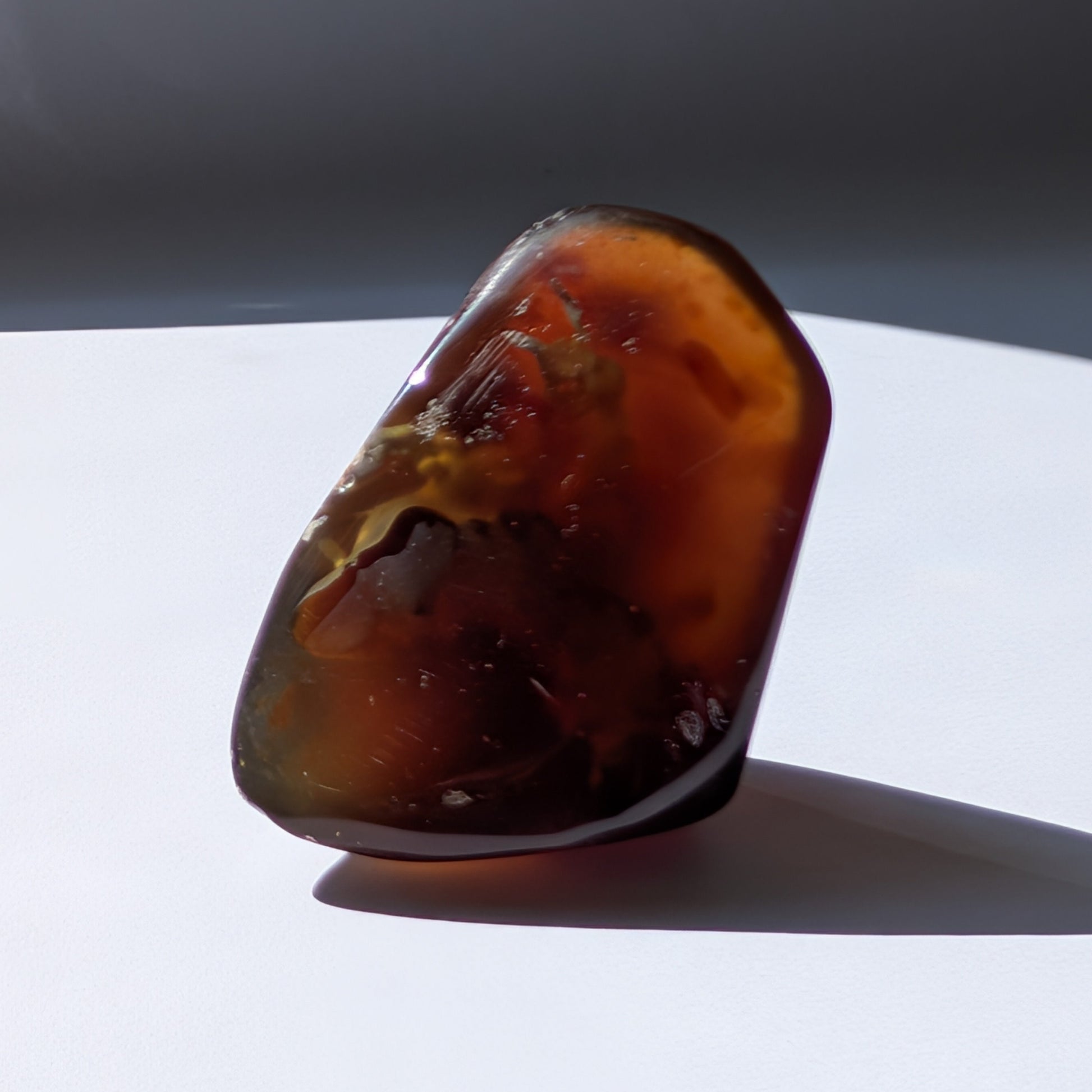 Bernstein Unikat "Die Träne der Sonne" in dunkler, tropfenartiger Form mit rotem Kern.