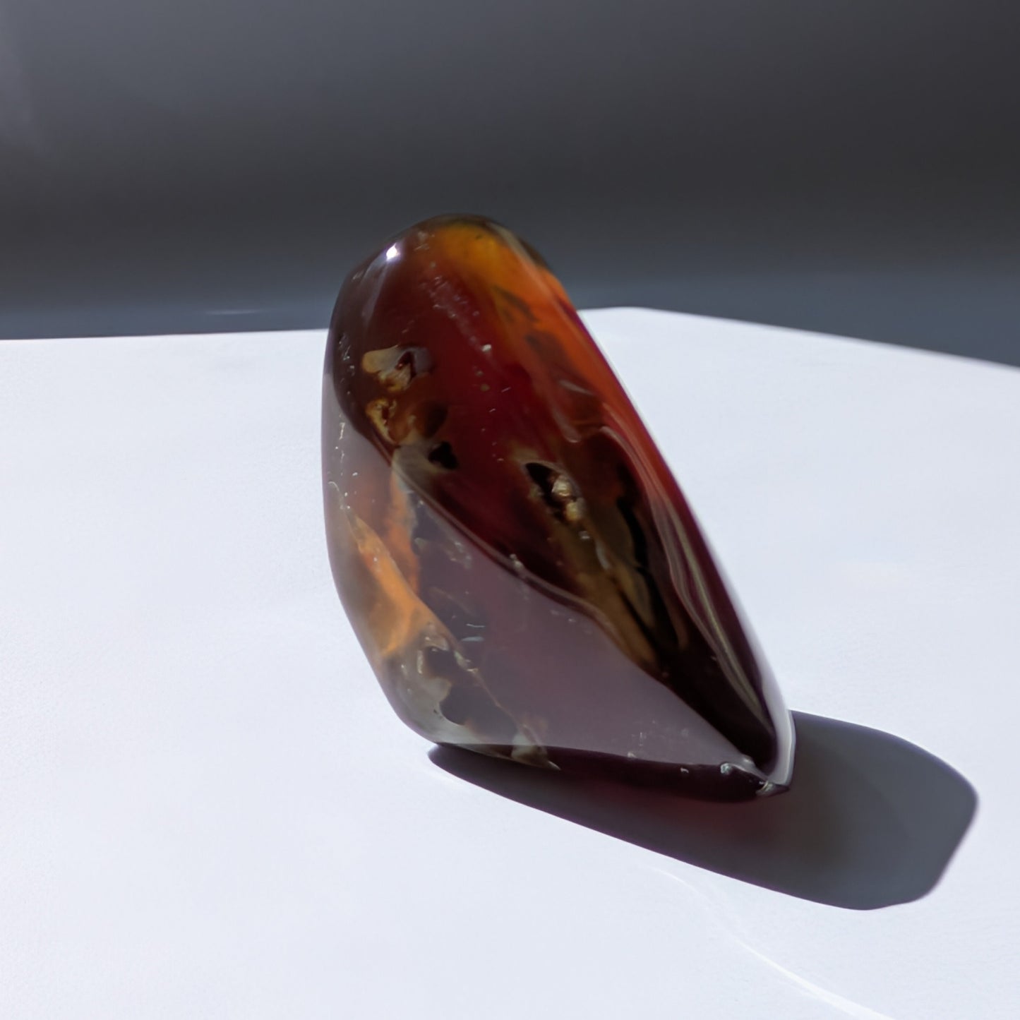 Bernstein Unikat "Die Träne der Sonne" in dunkler, tropfenartiger Form mit rotem Kern.