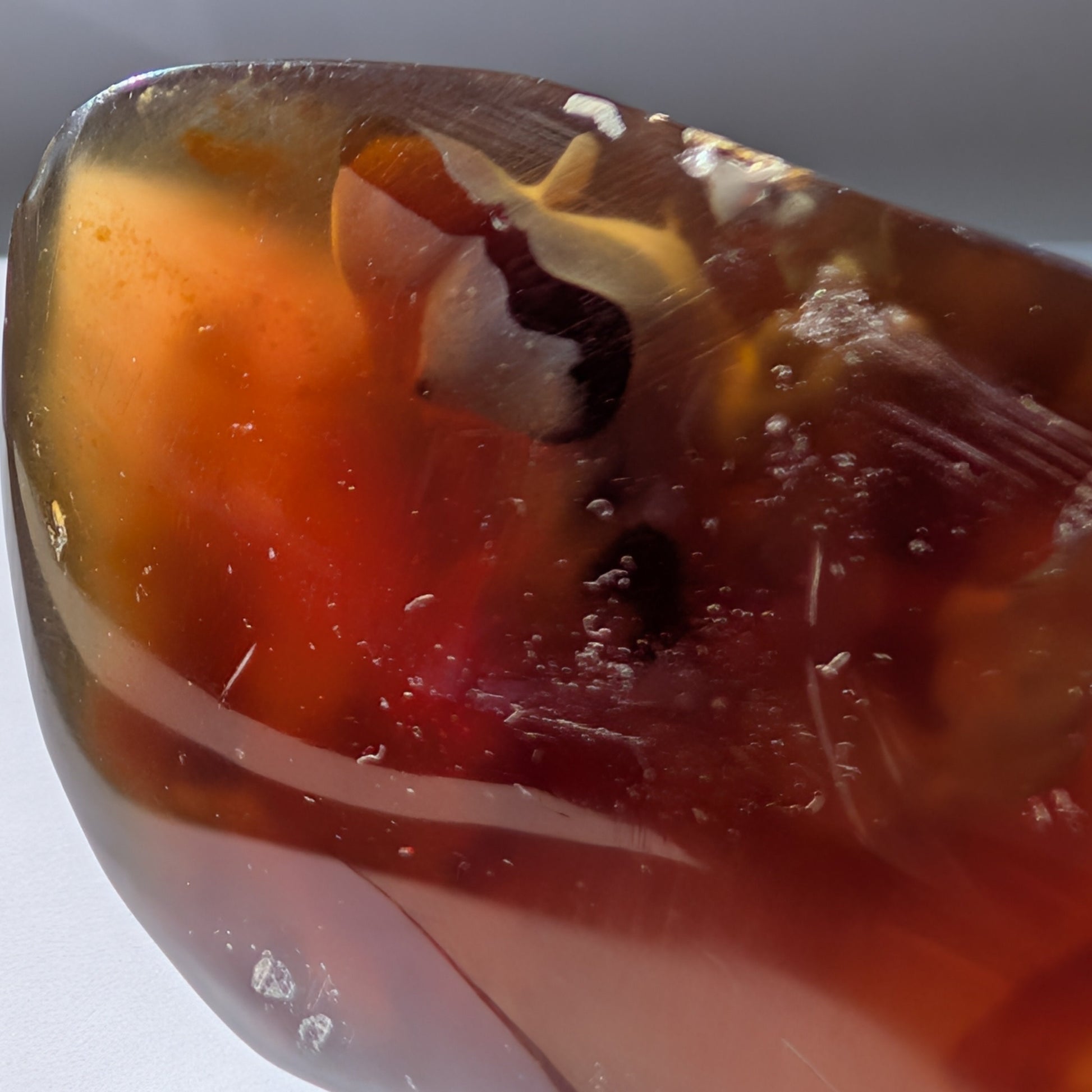 Bernstein Unikat "Die Träne der Sonne" in dunkler, tropfenartiger Form mit rotem Kern.