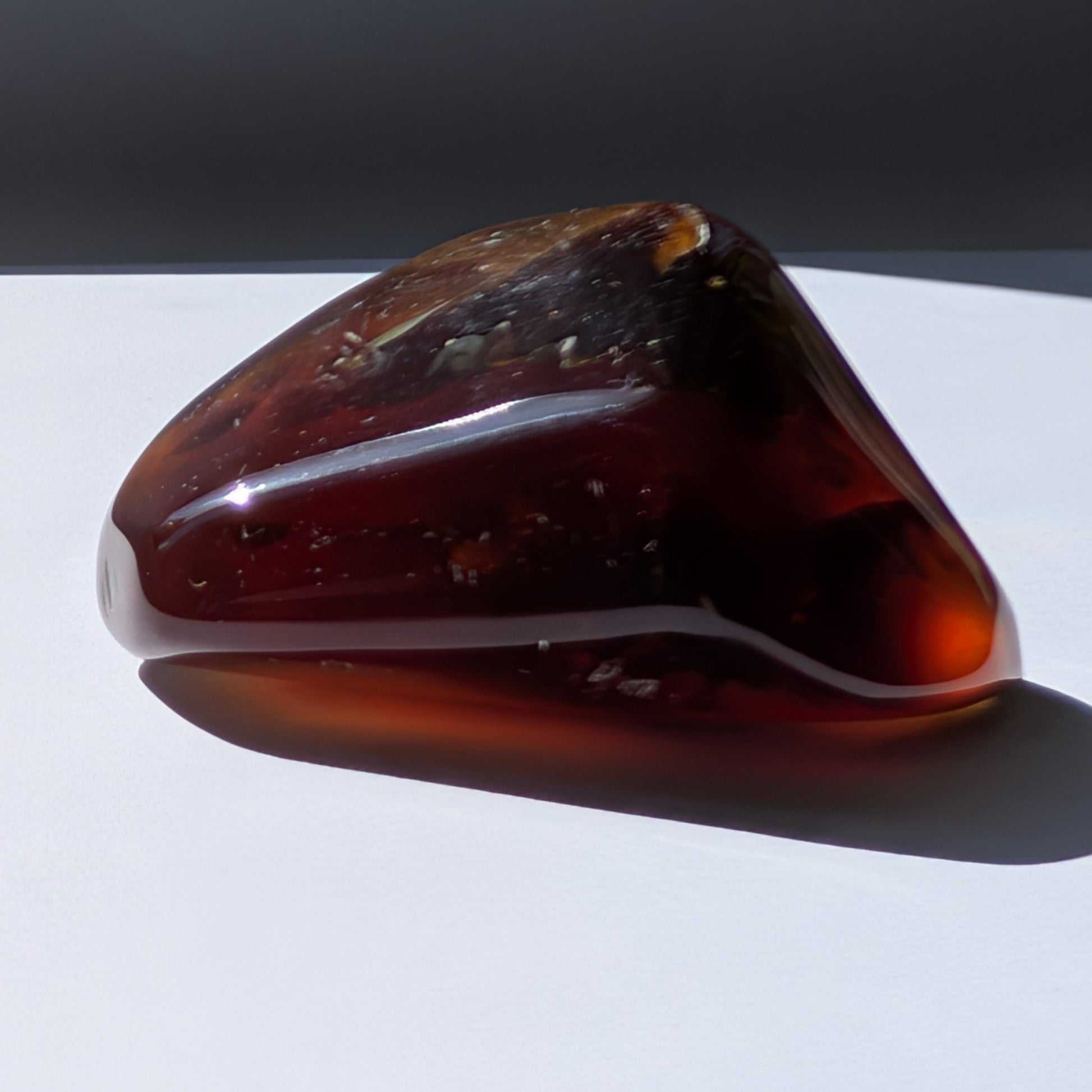 Bernstein Unikat "Die Träne der Sonne" in dunkler, tropfenartiger Form mit rotem Kern.