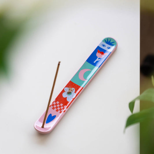 Bunter Räucherhalter von Helio Ferretti mit Glückssymbolen wie Nazar-Auge und Herz, in Benutzung mit rauchendem Stäbchen