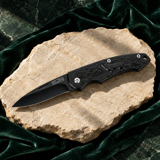CJH Taschenmesser Wolf mit schwarzer Klinge auf hellem Stein