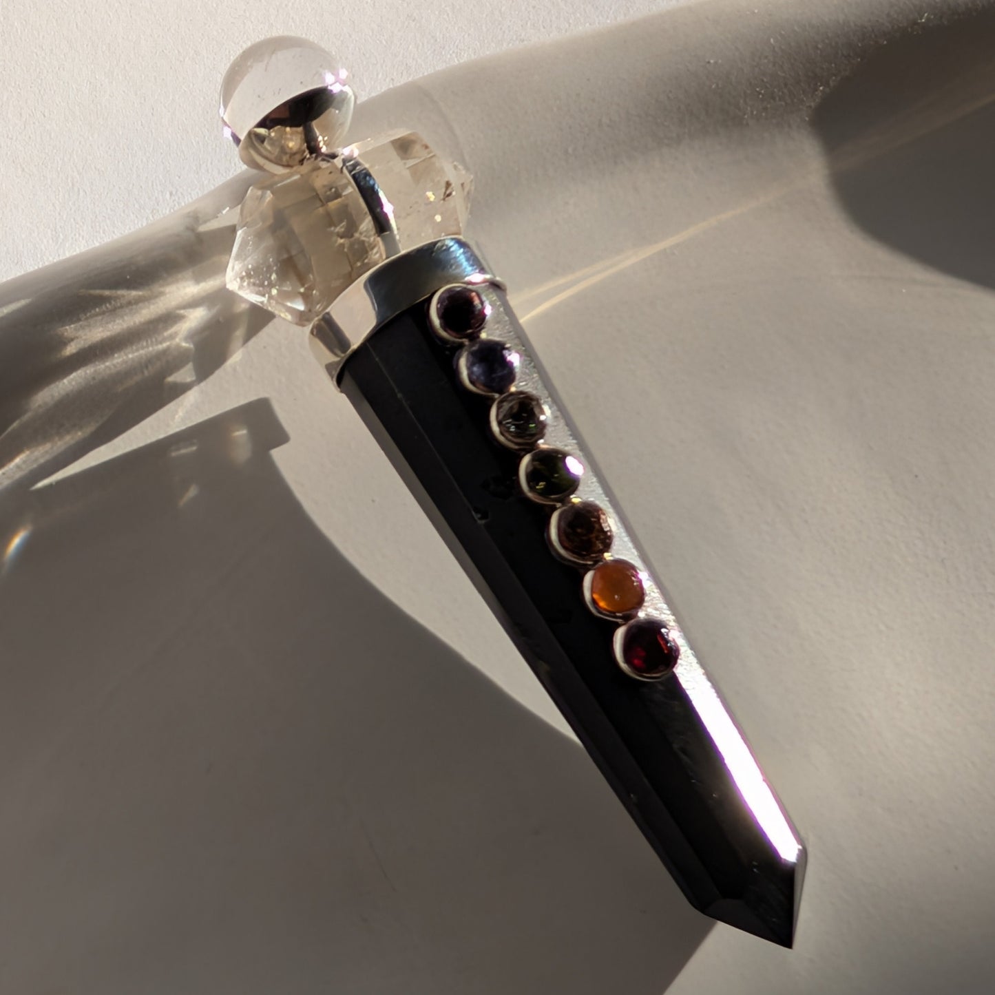 Chakra-Generatorstab aus schwarzem Schungit mit sieben farbigen Steinen und einer Bergkristall-Spitze.