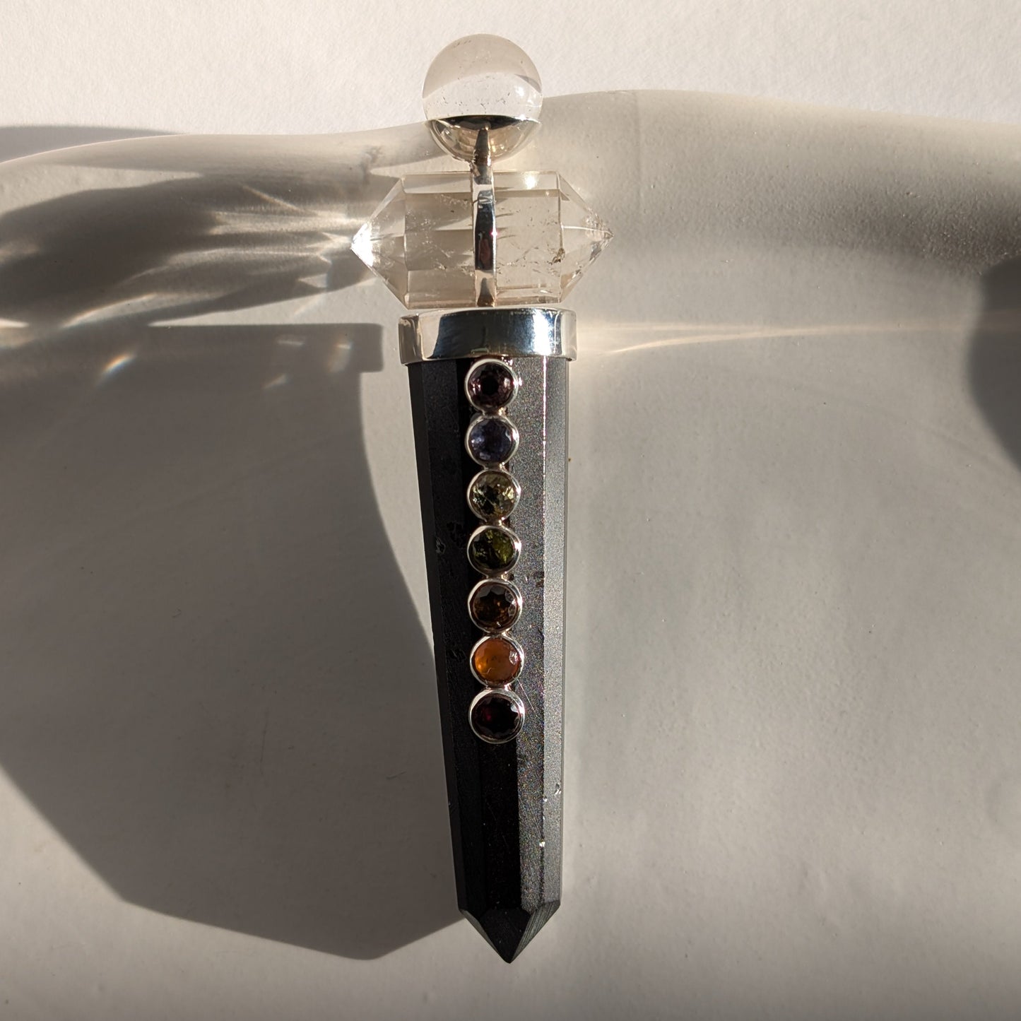 Chakra-Generatorstab aus schwarzem Schungit mit sieben farbigen Steinen und einer Bergkristall-Spitze.