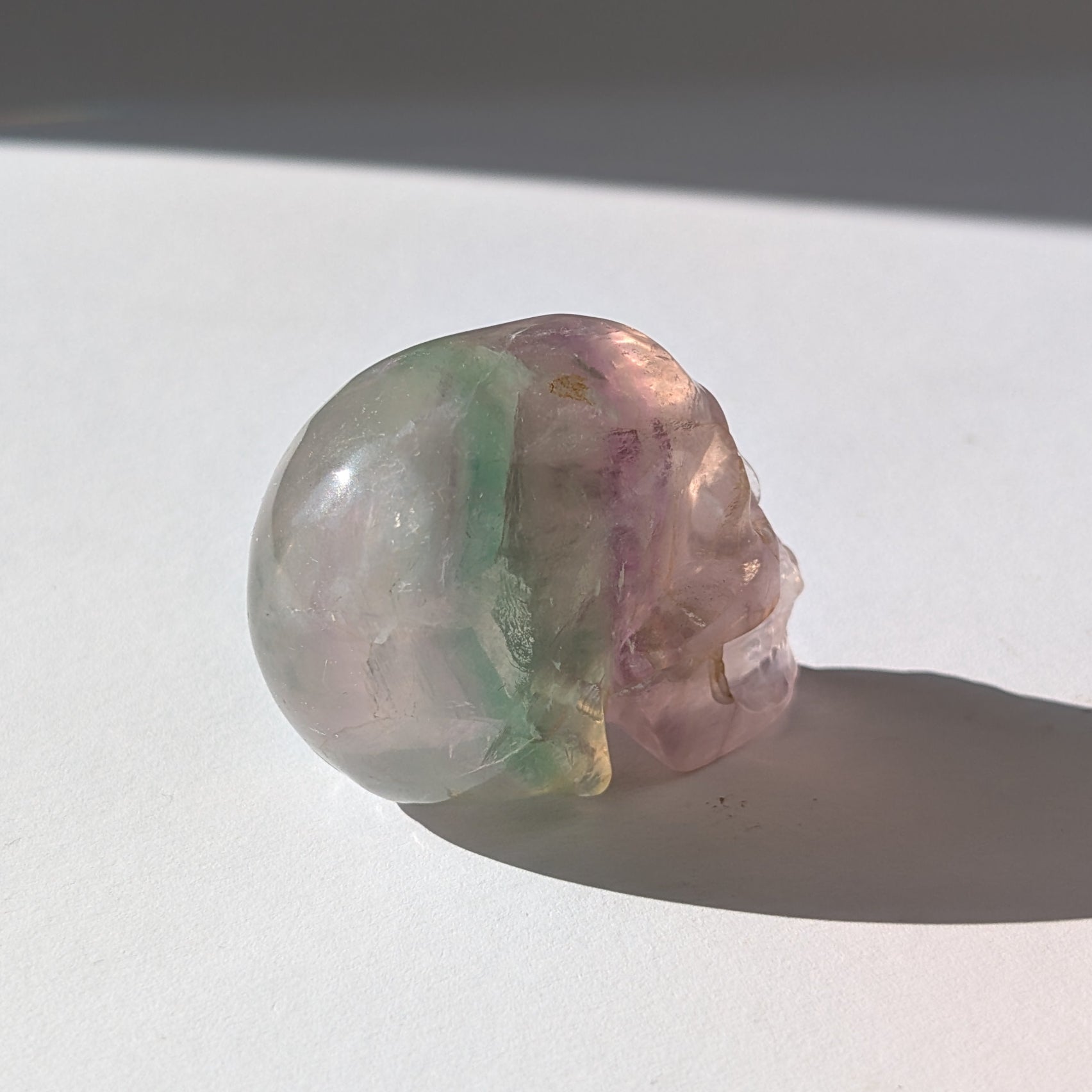 Ein 103g schwerer, handgeschnitzter Kristallschädel 'Uthar' aus durchscheinendem, grün-violettem Regenbogenfluorit.