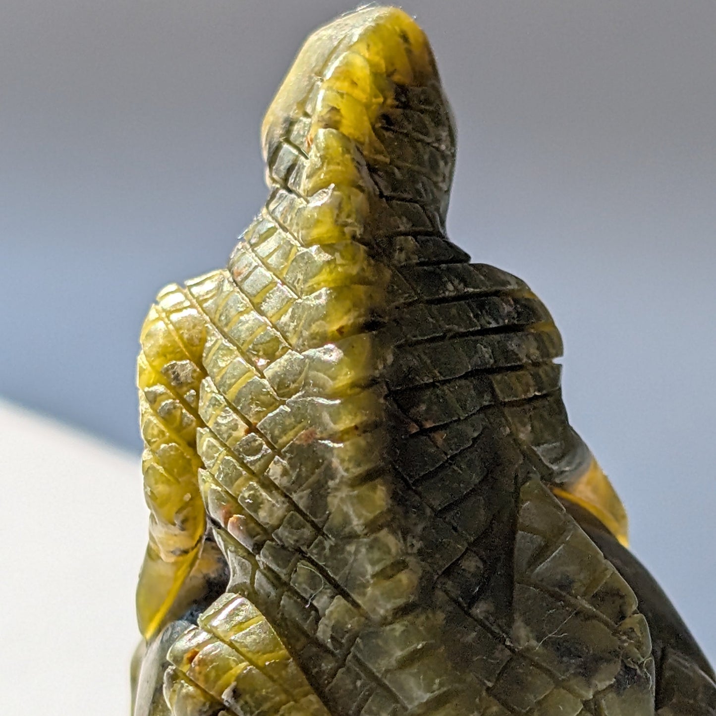 Ein 168g schwerer, handgeschnitzter Kristallschädel 'Veratha' aus grünem Serpentin, mit einer detailreichen Kobra, die sich auf seinem Scheitel aufrichtet.