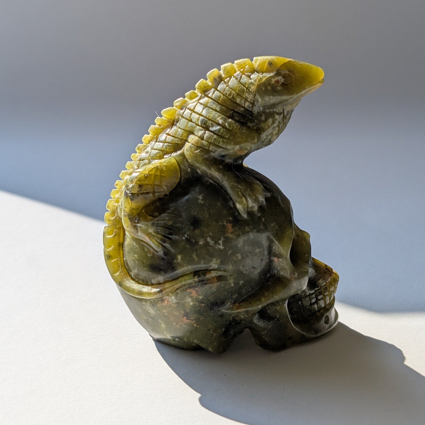 Ein 168g schwerer, handgeschnitzter Kristallschädel 'Veratha' aus grünem Serpentin, mit einer detailreichen Kobra, die sich auf seinem Scheitel aufrichtet.