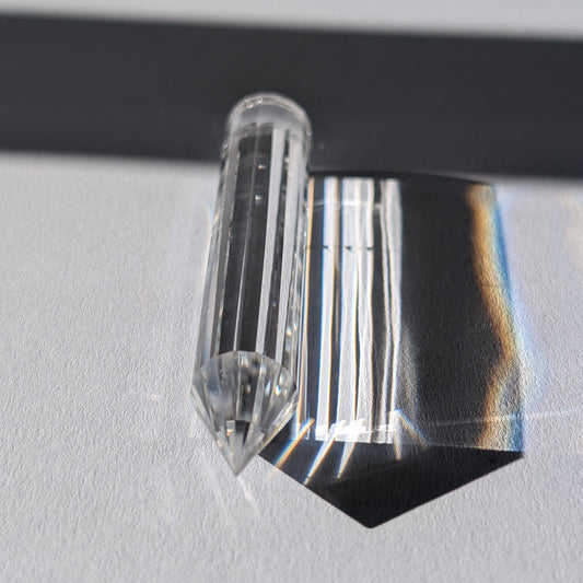 Ein 24-fach gerillter (fluted) Heilerstab aus wasserklarem Bergkristall (50g), der Licht reflektiert.