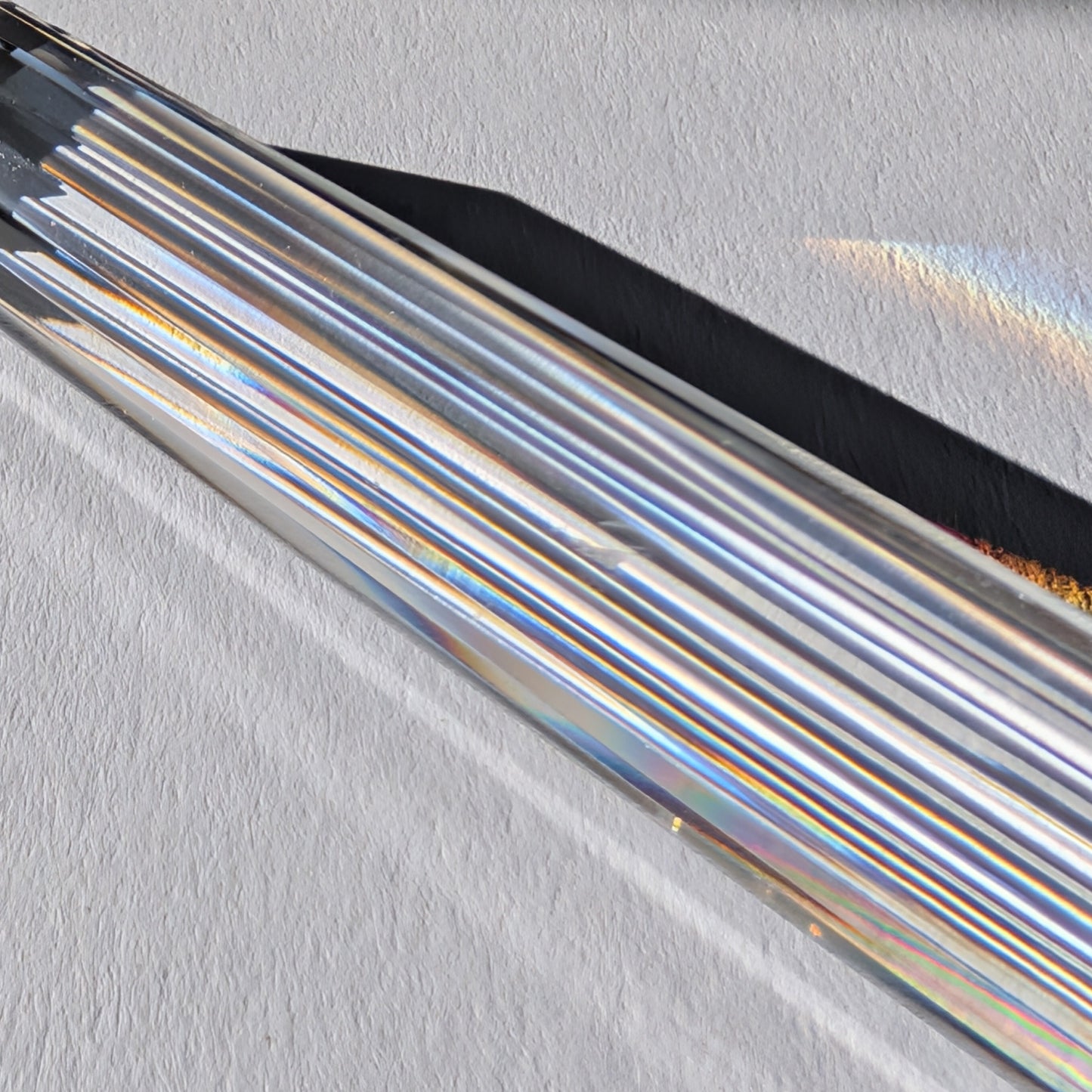 Ein 24-fach gerillter (fluted) Heilerstab aus wasserklarem Bergkristall (50g), der Licht reflektiert.