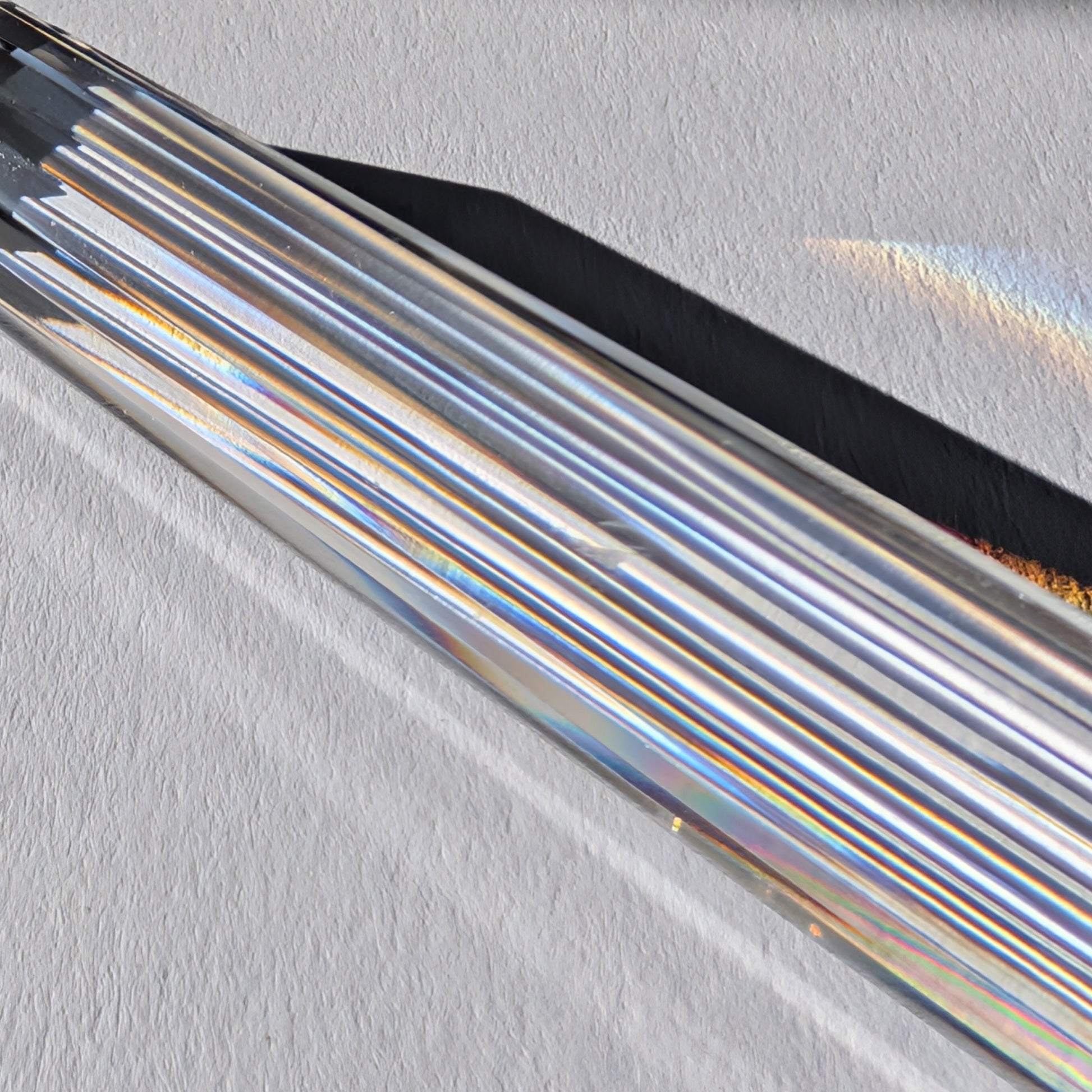 Ein 24-fach gerillter (fluted) Heilerstab aus wasserklarem Bergkristall (50g), der Licht reflektiert.