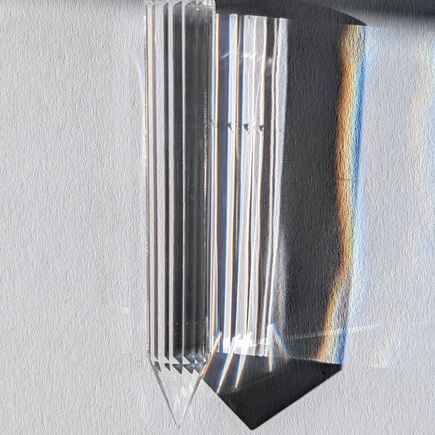 Ein 24-fach gerillter (fluted) Heilerstab aus wasserklarem Bergkristall (50g), der Licht reflektiert.