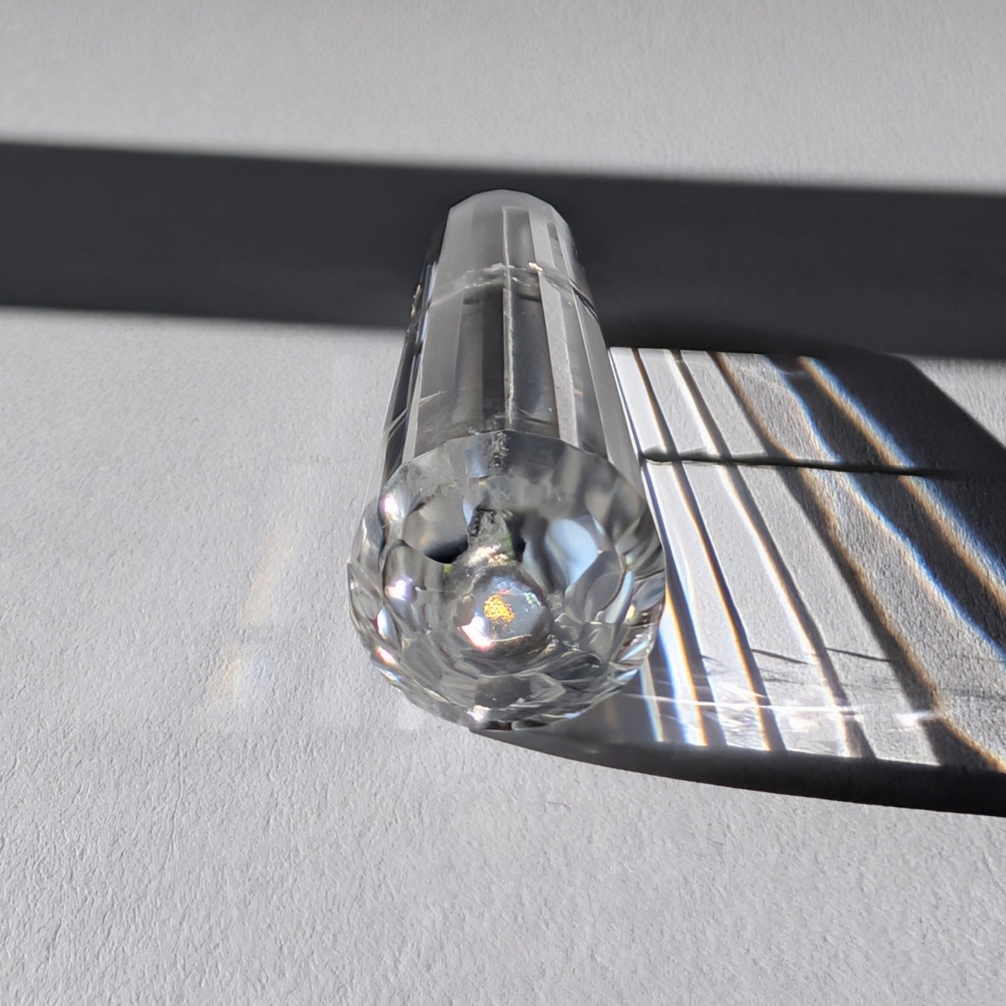 Ein 24-fach gerillter (fluted) Heilerstab aus wasserklarem Bergkristall (59g) im Licht.