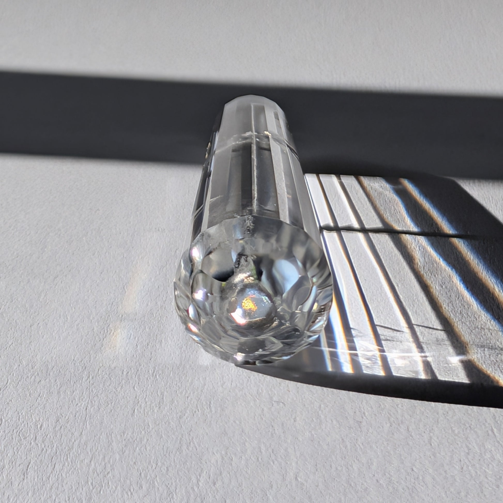 Ein 24-fach gerillter (fluted) Heilerstab aus wasserklarem Bergkristall (59g) im Licht.