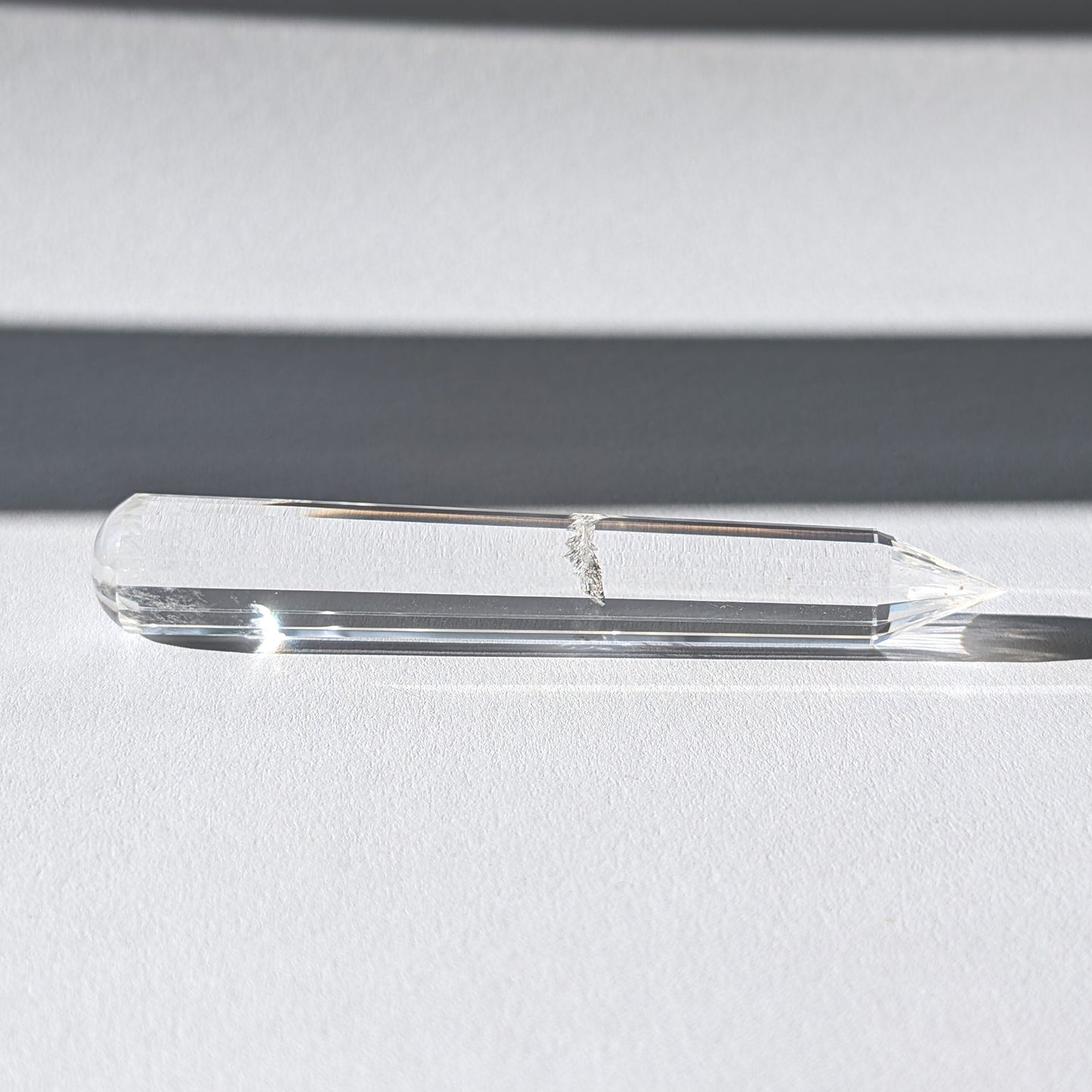 Ein 24-fach gerillter (fluted) Heilerstab aus wasserklarem Bergkristall (59g) im Licht.