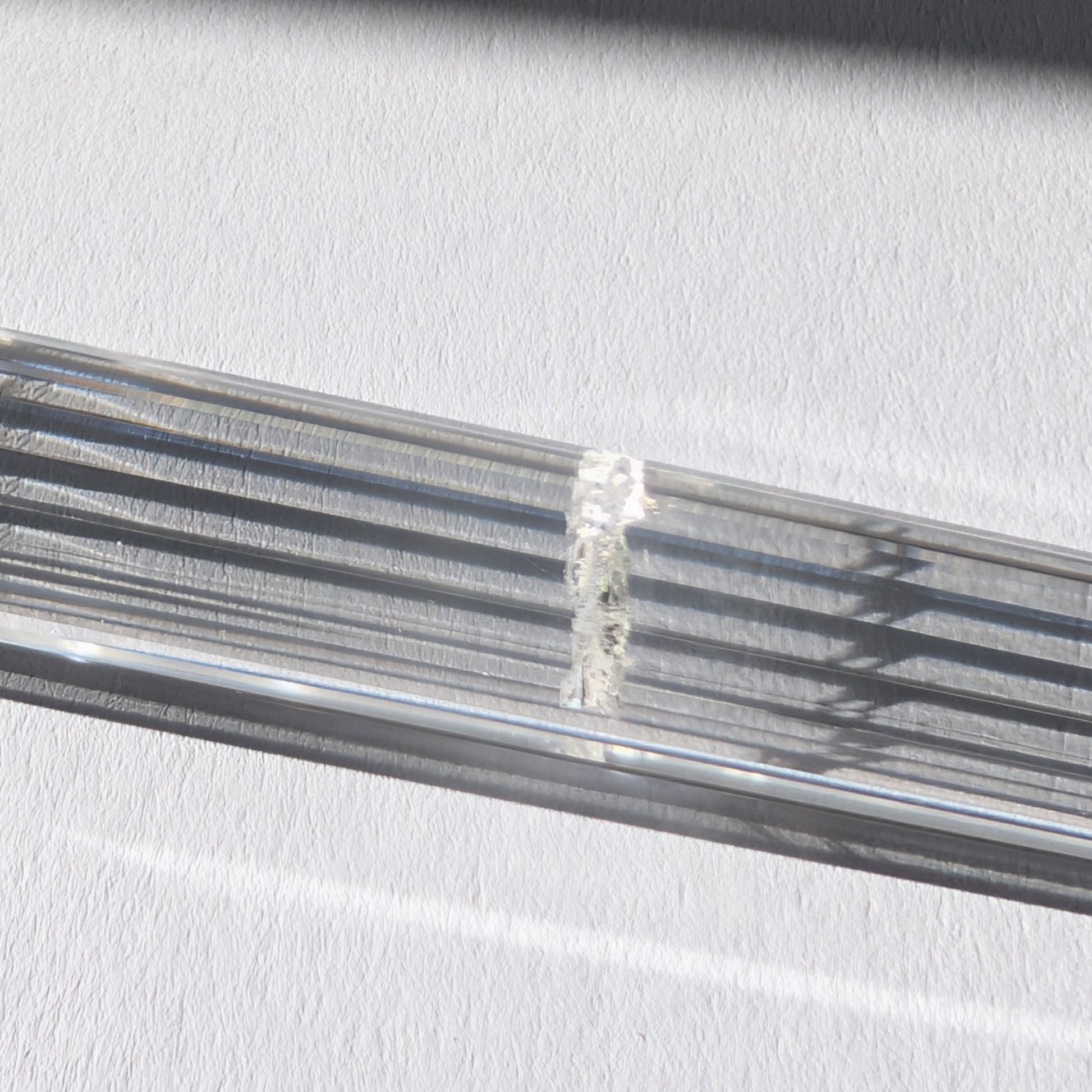 Ein 24-fach gerillter (fluted) Heilerstab aus wasserklarem Bergkristall (59g) im Licht.