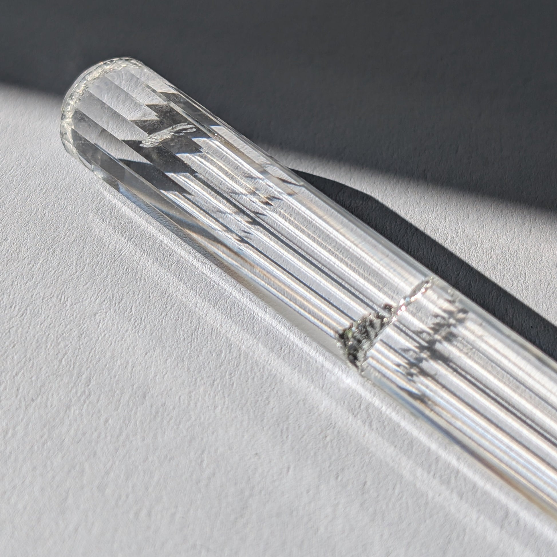 Ein 24-fach gerillter (fluted) Heilerstab aus wasserklarem Bergkristall (59g) im Licht.