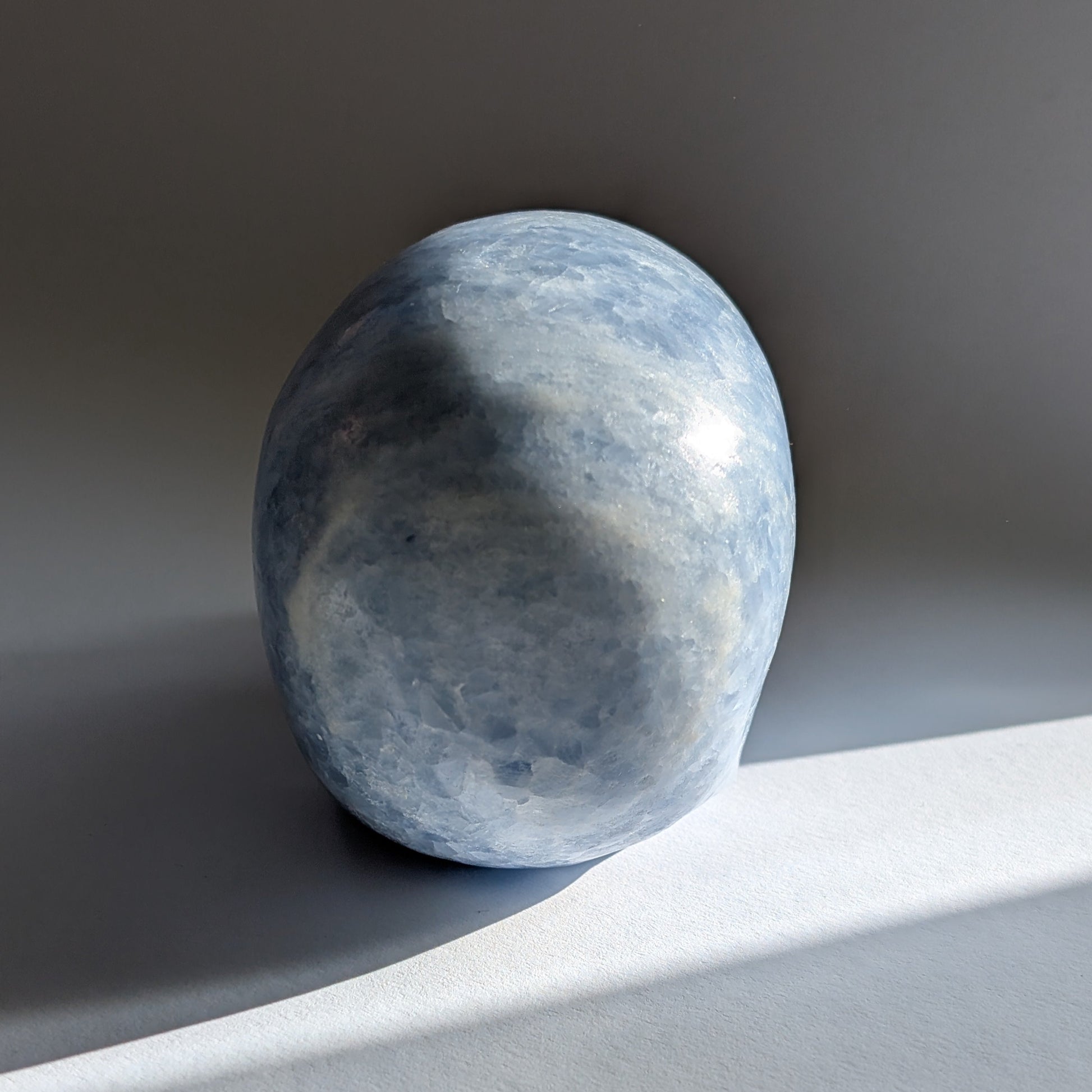Ein 660g schwerer, handgeschnitzter Kristallschädel 'Hulu' aus zartblauem bis weißem Anhydrit, der eine friedvolle Energie ausstrahlt.