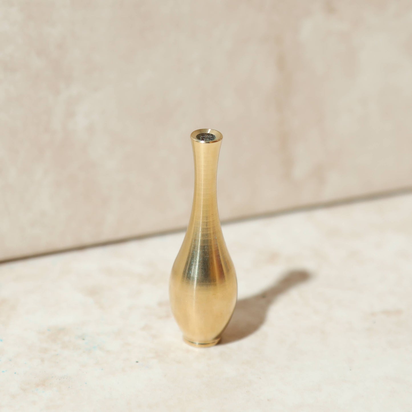 Ein eleganter, vasenförmiger Räucherstäbchenhalter 'Altar-Vase' aus massivem Messing, der ein Räucherstäbchen hält.