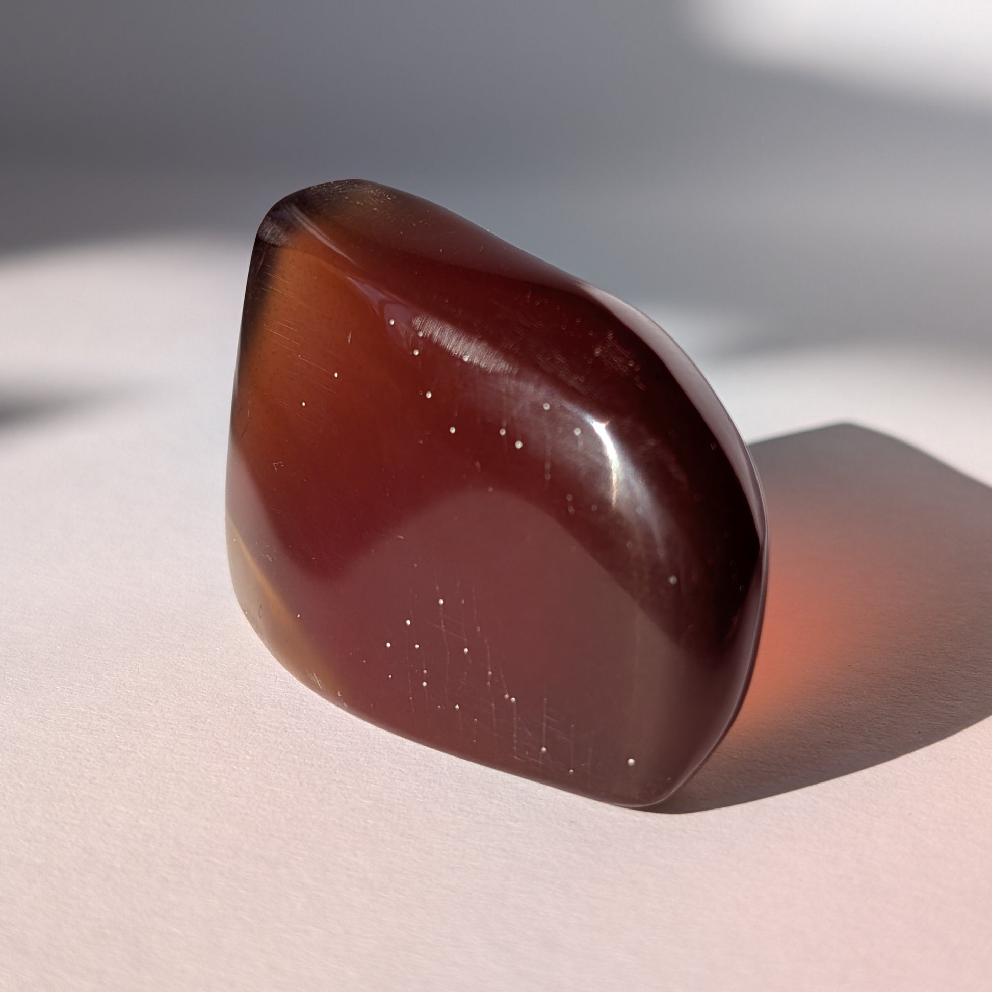 Ein großer, polierter Bicolor-Bernstein 'Die sanfte Flamme der Vorzeit', der sanft von tiefem Rot in einen goldenen Cognac-Ton übergeht.