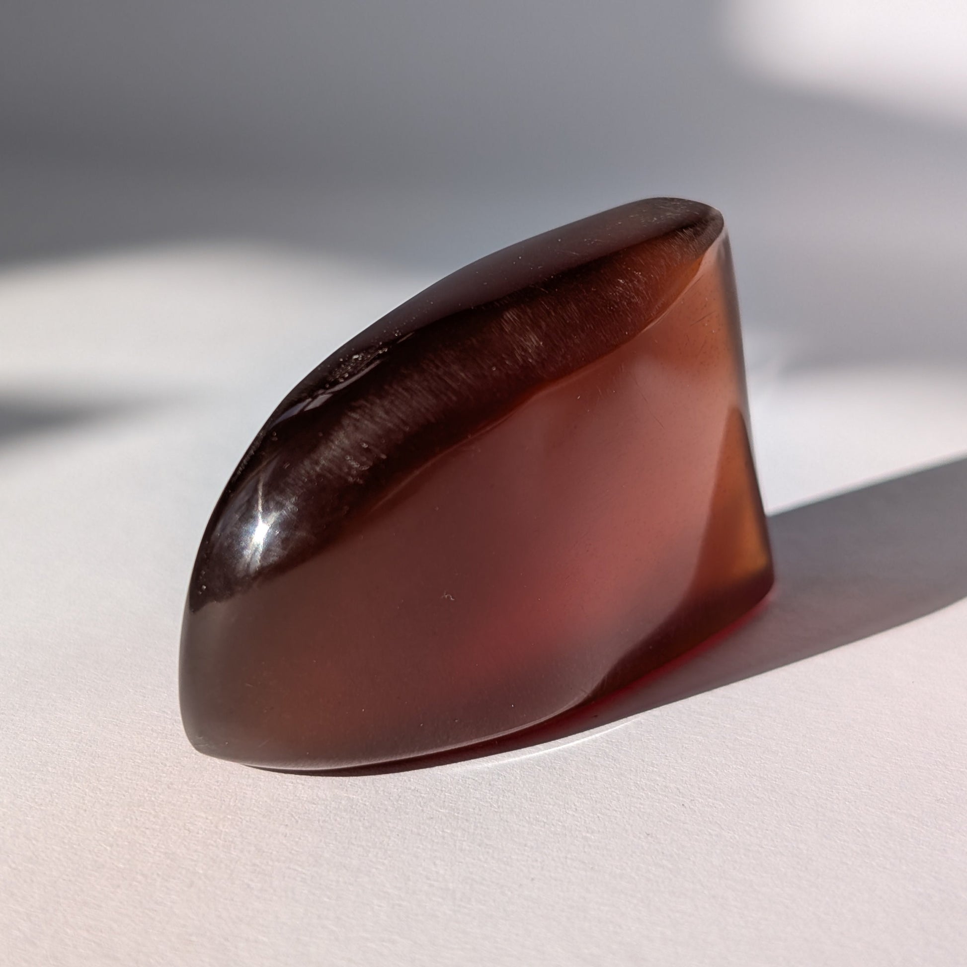 Ein großer, polierter Bicolor-Bernstein 'Die sanfte Flamme der Vorzeit', der sanft von tiefem Rot in einen goldenen Cognac-Ton übergeht.