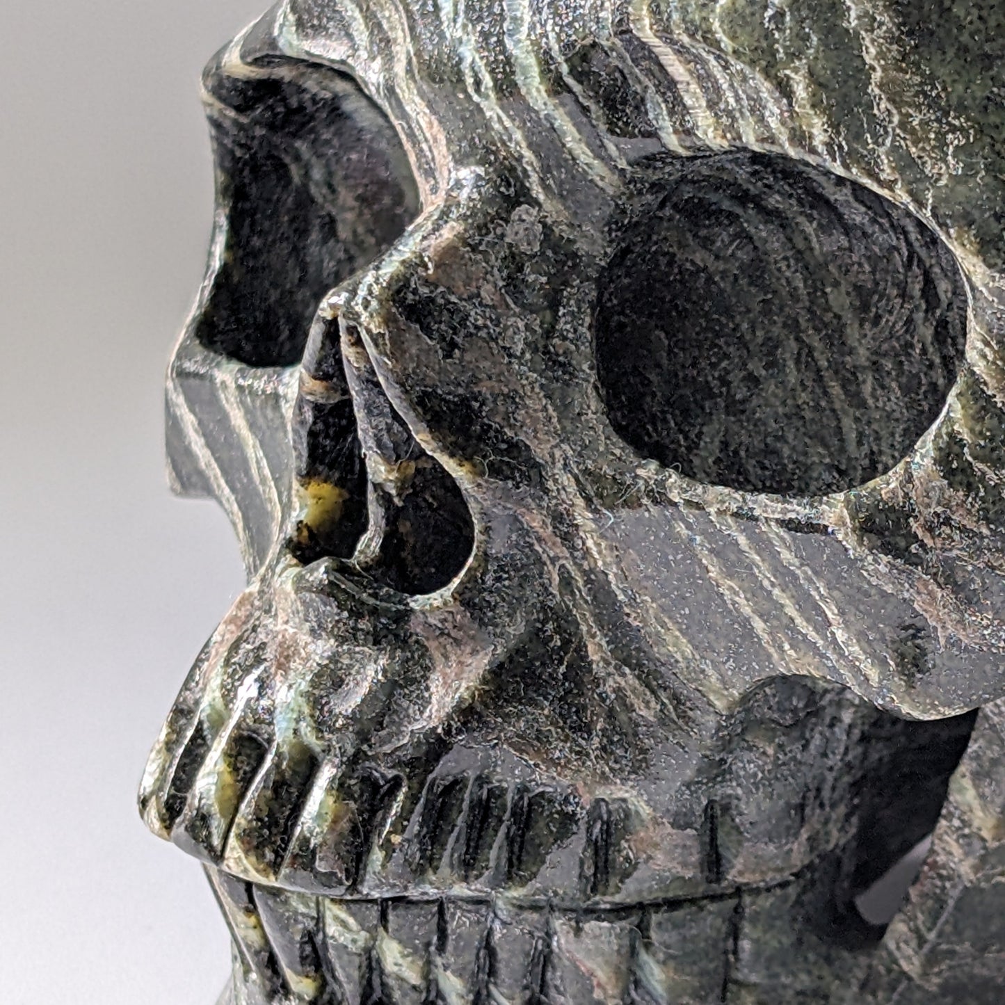 Ein monumentaler, 1204g schwerer Kristallschädel 'Scryer' aus dunkelgrünem Serpentin mit hypnotisierendem, silbrigem Schimmer.