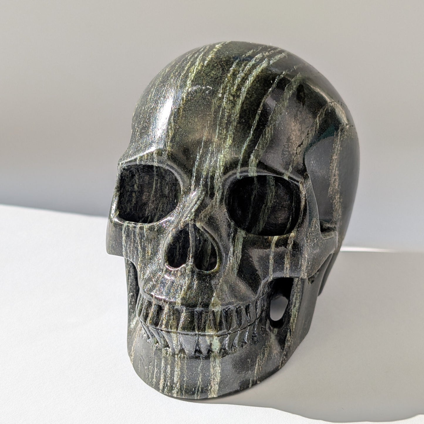 Ein monumentaler, 1346g schwerer Kristallschädel 'Der Wächter der Lebenskraft' aus Serpentin mit einem hypnotisierenden, silbrig-grünen Schimmer.