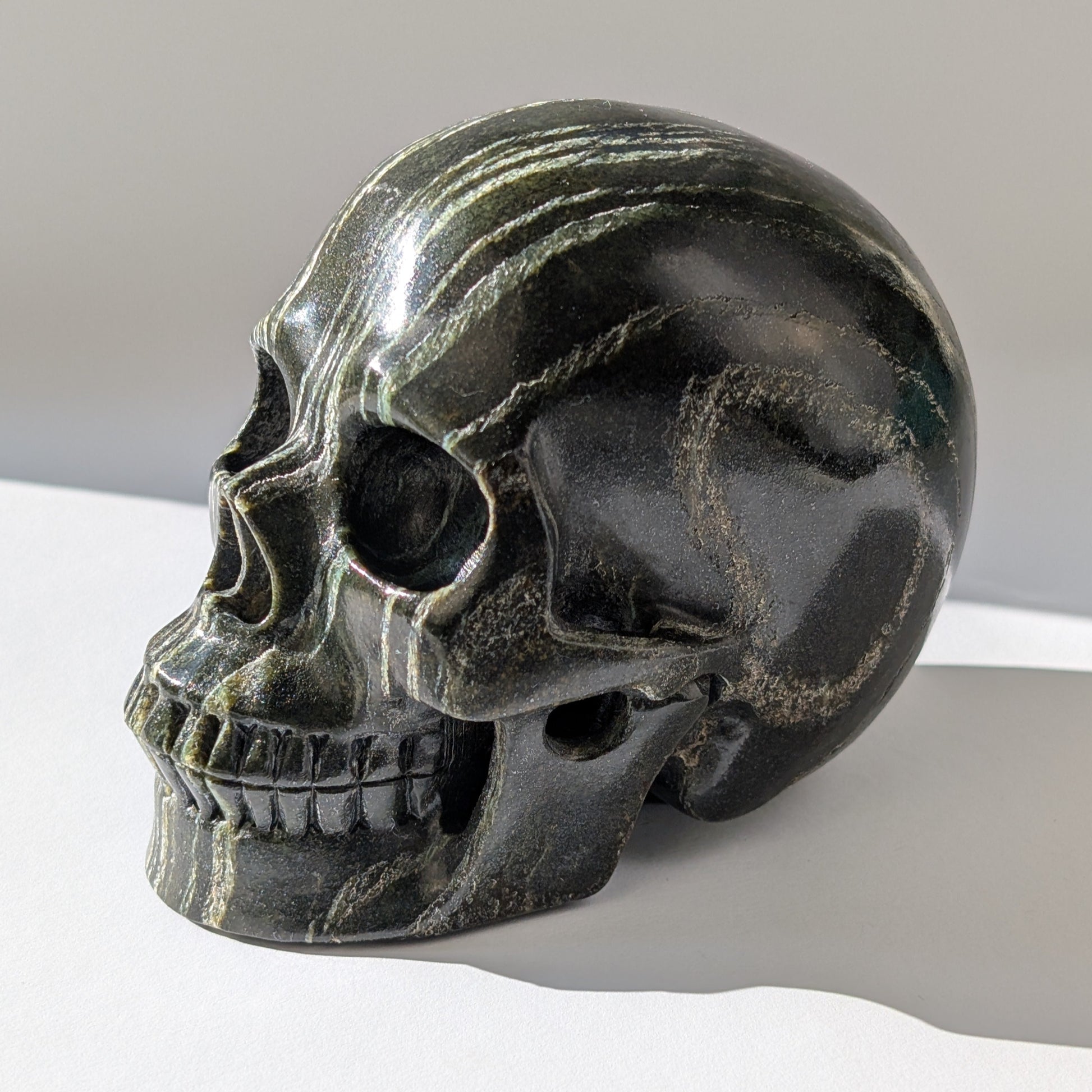 Ein monumentaler, 1346g schwerer Kristallschädel 'Der Wächter der Lebenskraft' aus Serpentin mit einem hypnotisierenden, silbrig-grünen Schimmer.