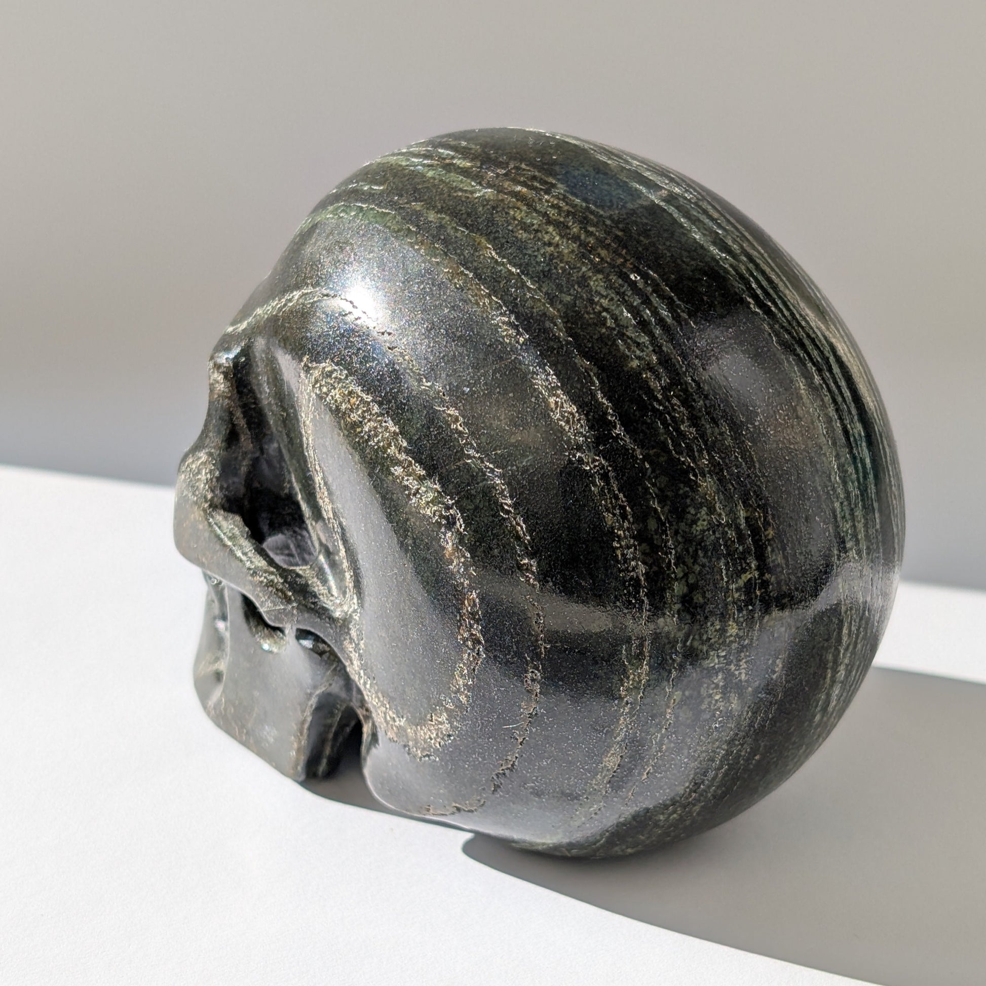 Ein monumentaler, 1346g schwerer Kristallschädel 'Der Wächter der Lebenskraft' aus Serpentin mit einem hypnotisierenden, silbrig-grünen Schimmer.
