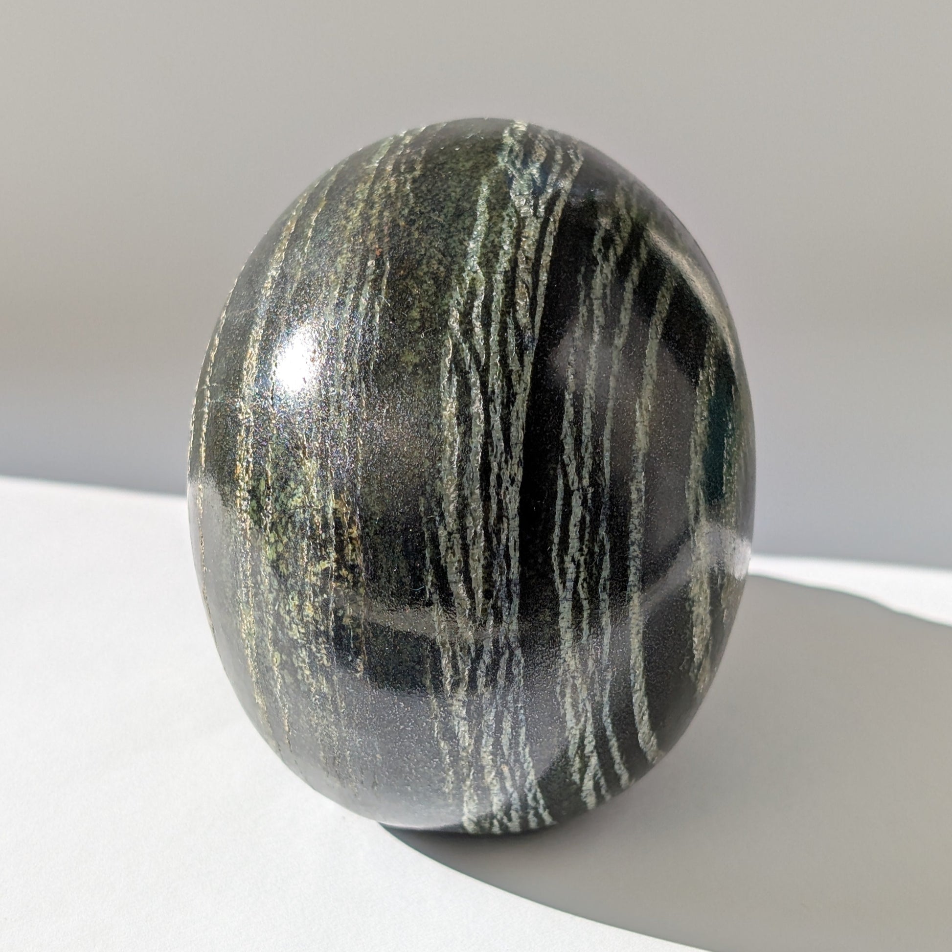 Ein monumentaler, 1346g schwerer Kristallschädel 'Der Wächter der Lebenskraft' aus Serpentin mit einem hypnotisierenden, silbrig-grünen Schimmer.