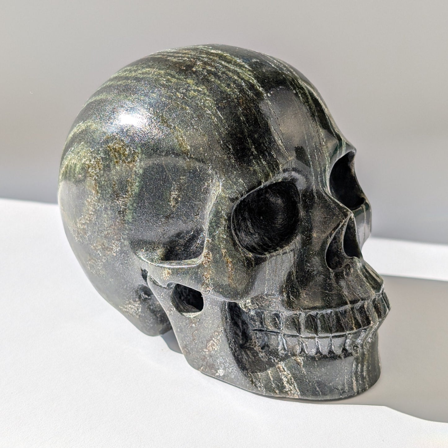 Ein monumentaler, 1346g schwerer Kristallschädel 'Der Wächter der Lebenskraft' aus Serpentin mit einem hypnotisierenden, silbrig-grünen Schimmer.