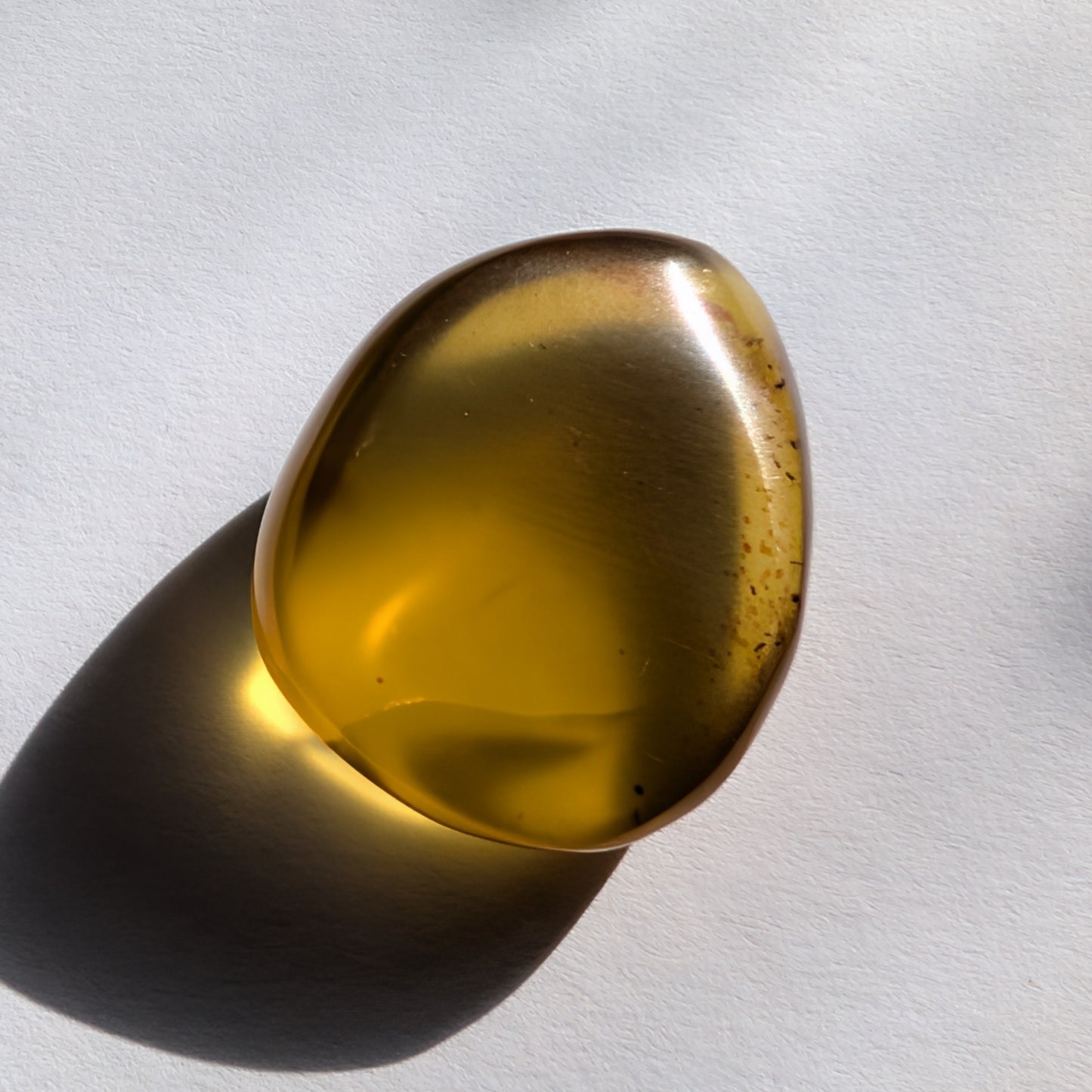 Ein polierter Bicolor-Bernstein 'Der Tropfen der Sonne' in natürlicher Freiform, der von Cognac-braun zu leuchtendem Sonnengelb übergeht.