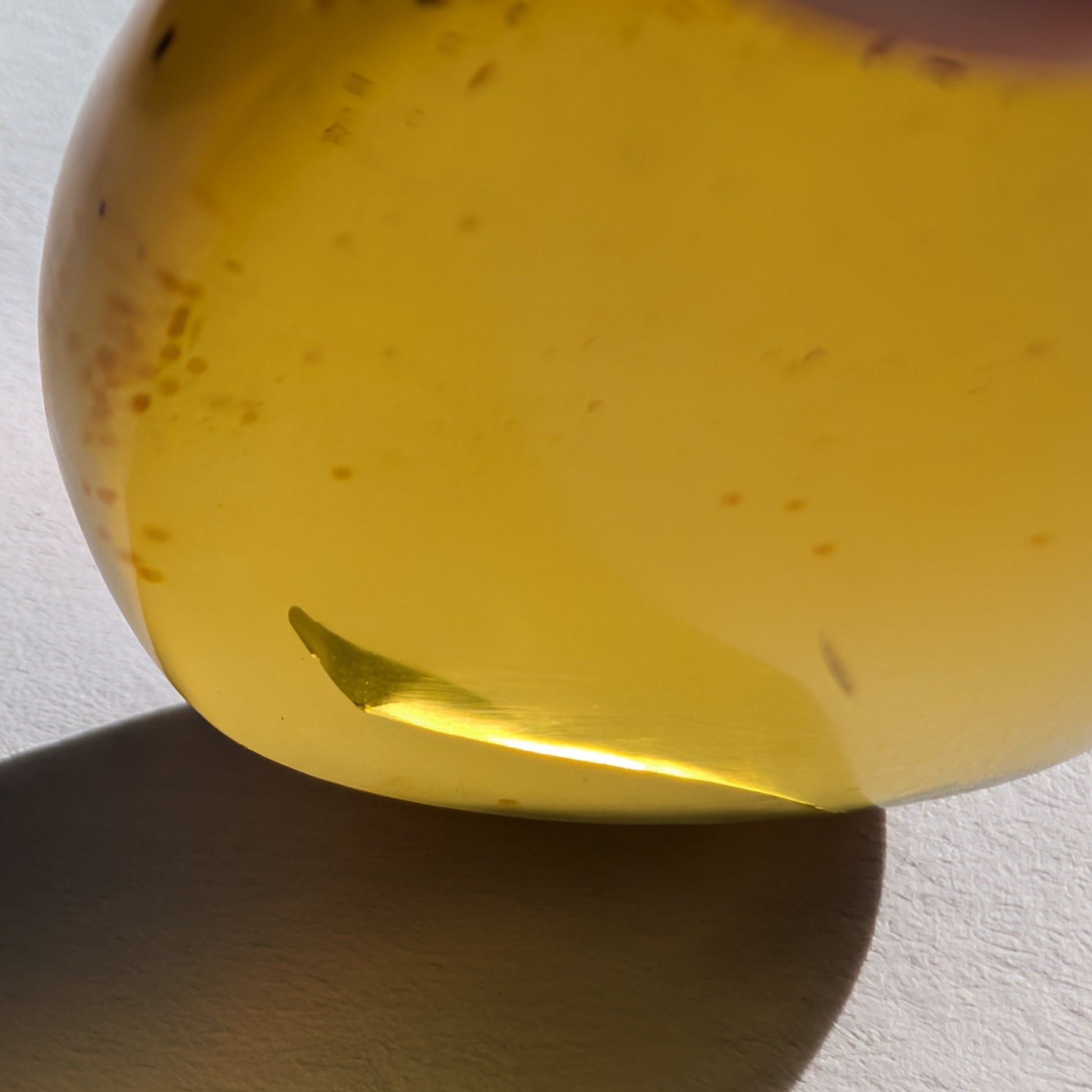 Ein polierter Bicolor-Bernstein 'Der Tropfen der Sonne' in natürlicher Freiform, der von Cognac-braun zu leuchtendem Sonnengelb übergeht.